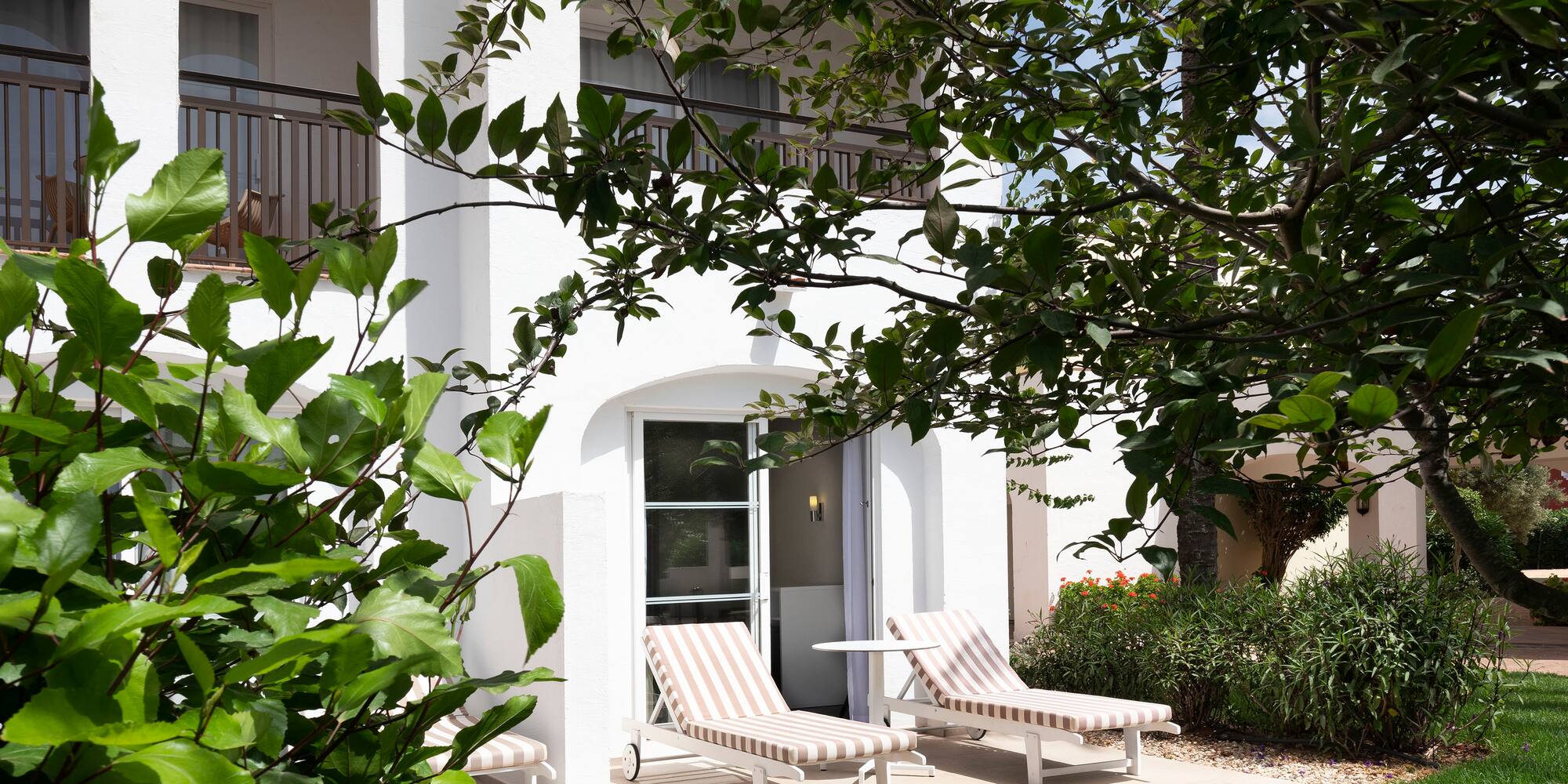 a white building with lawn chairs and trees