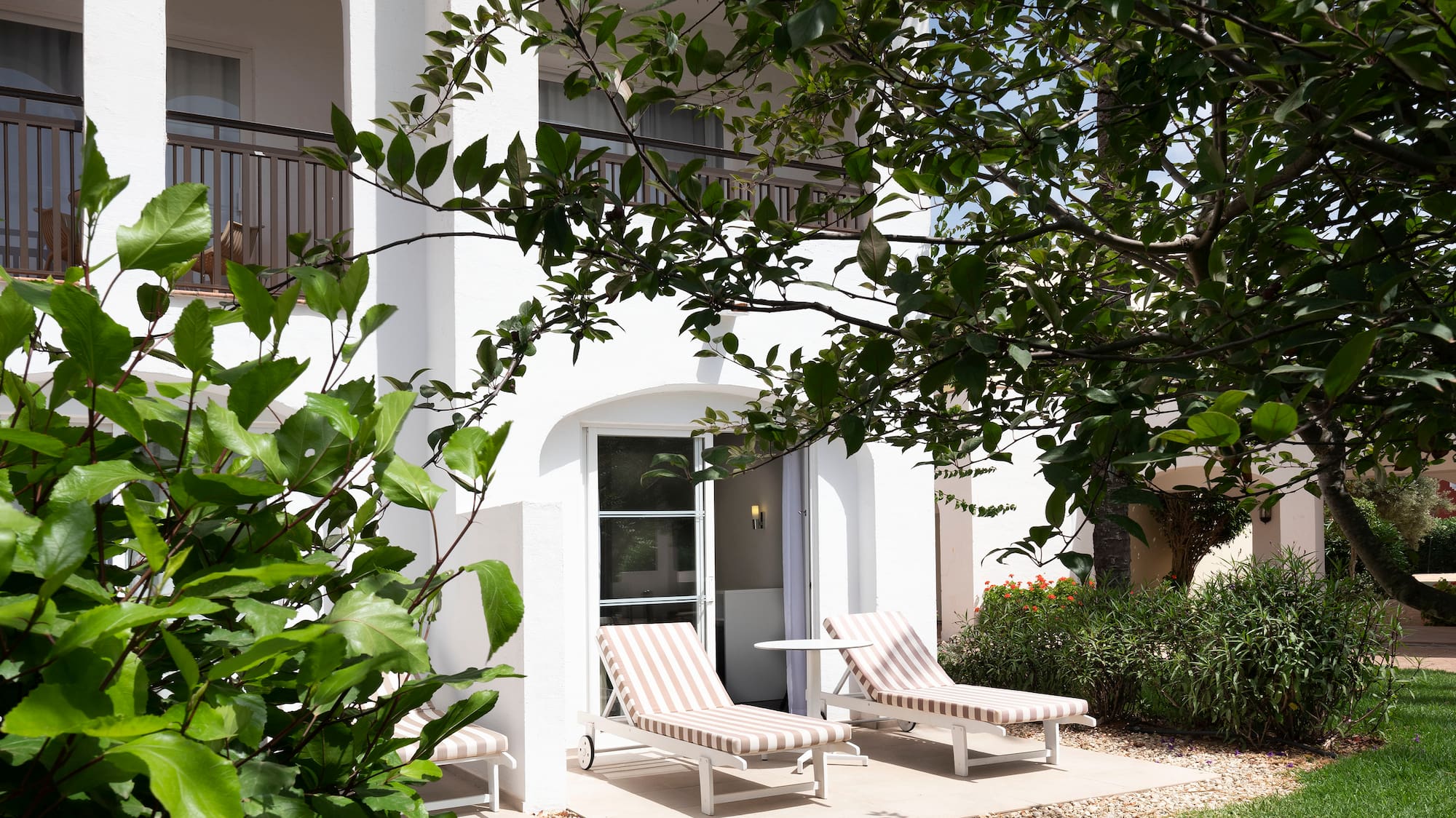 a white building with lawn chairs and trees