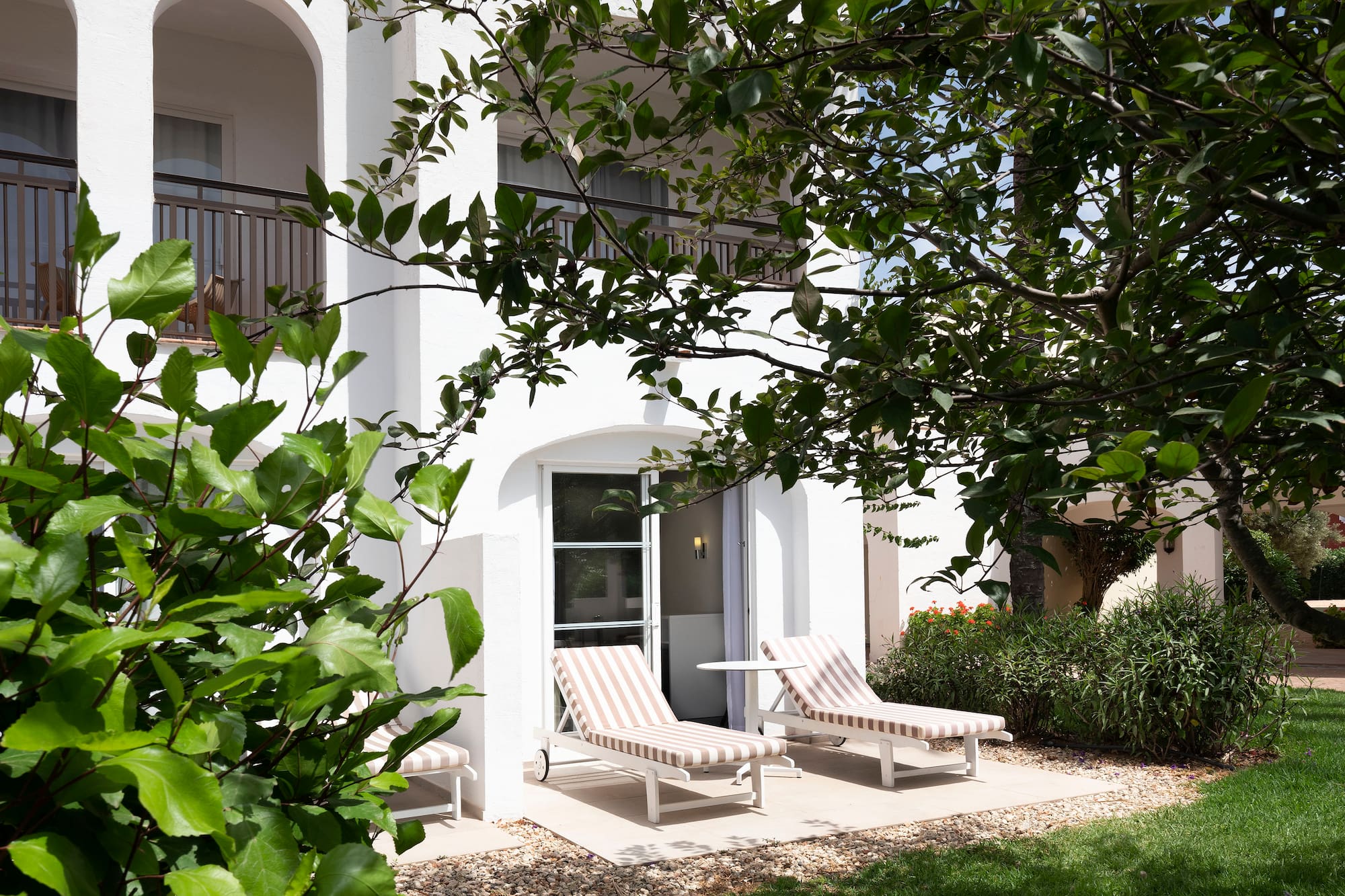 a white building with lawn chairs and trees