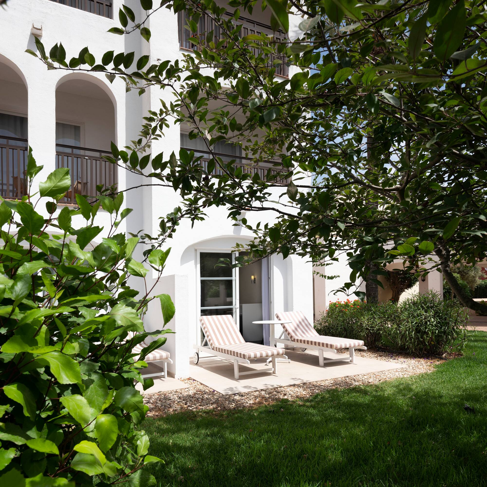 a white building with lawn chairs and trees