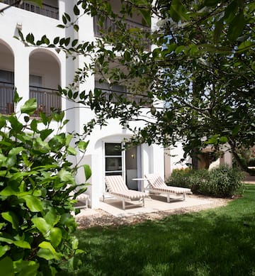 a white building with lawn chairs and trees