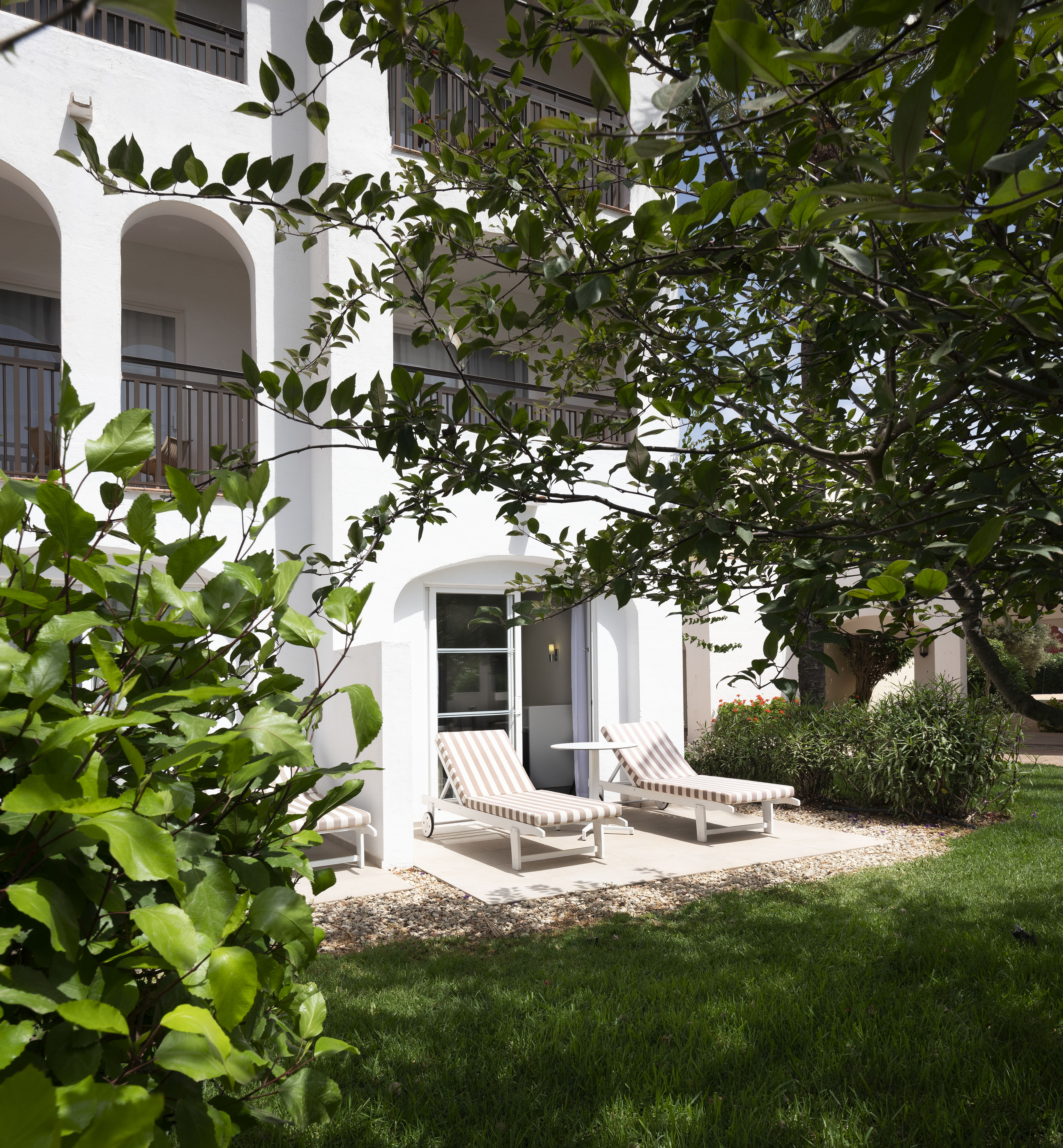 a white building with lawn chairs and trees