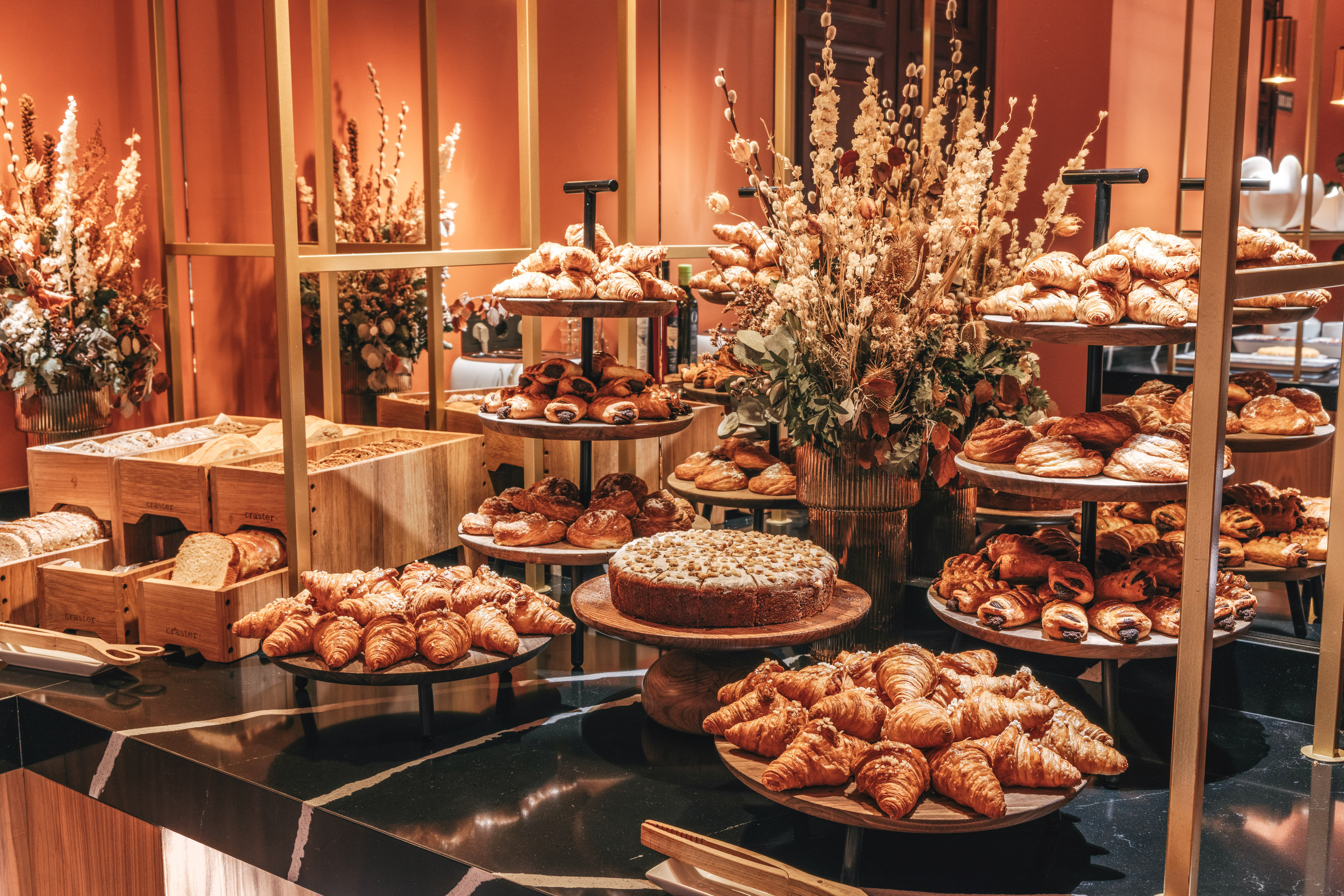 Fresh croissants, pastries, bread, and cake at a breakfast buffet.