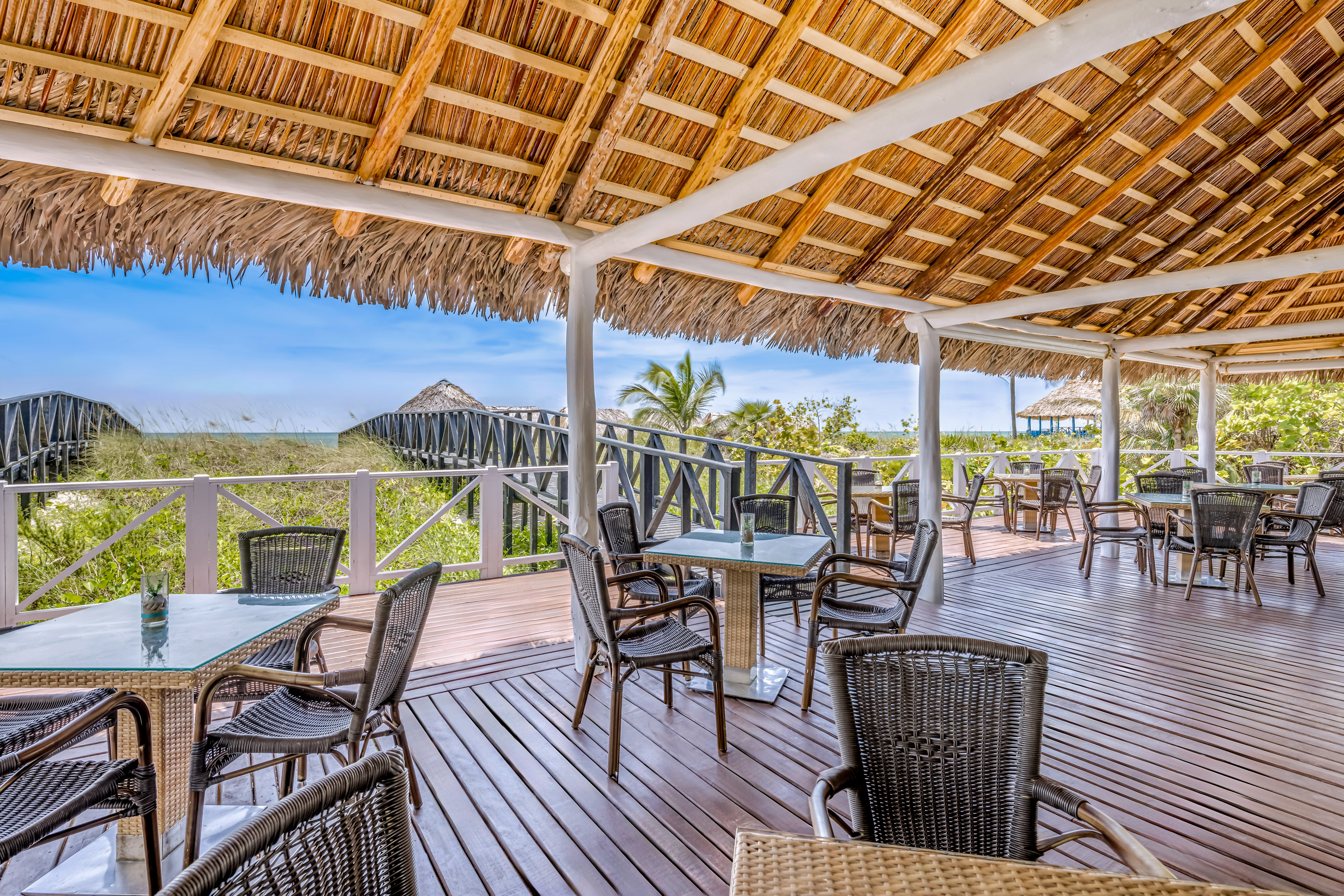 a deck with chairs and a thatched roof