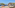 Resort terrace with cabana daybeds, potted olive trees, and a clear sea view.