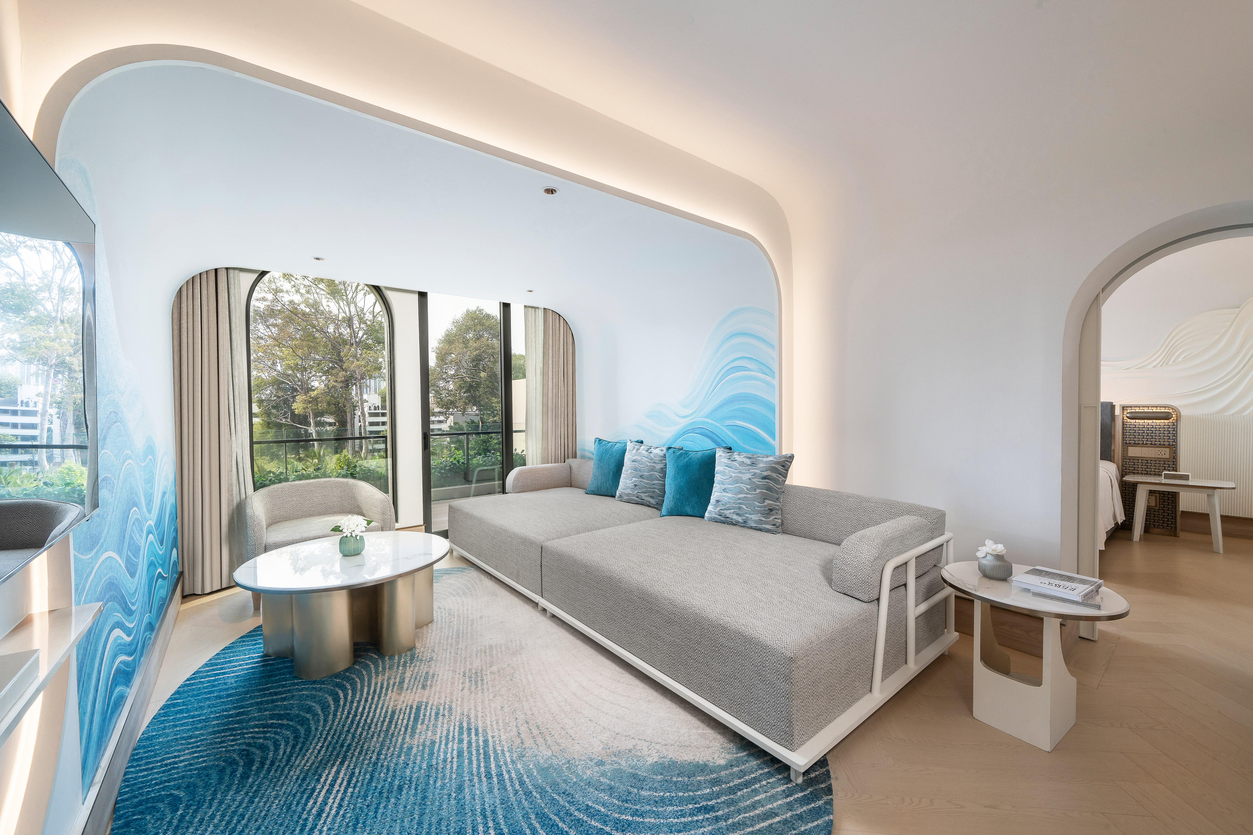 Modern hotel suite living room with grey sofa, blue wavy rug, and large windows. - The Level 2 Bedroom Suite - Meliá Pattaya Hotel, Pattaya