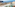 Balcony ocean view: green chair, coastal town, blue sea, cliffs.