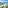 Balcony ocean view: green chair, coastal town, blue sea, cliffs.