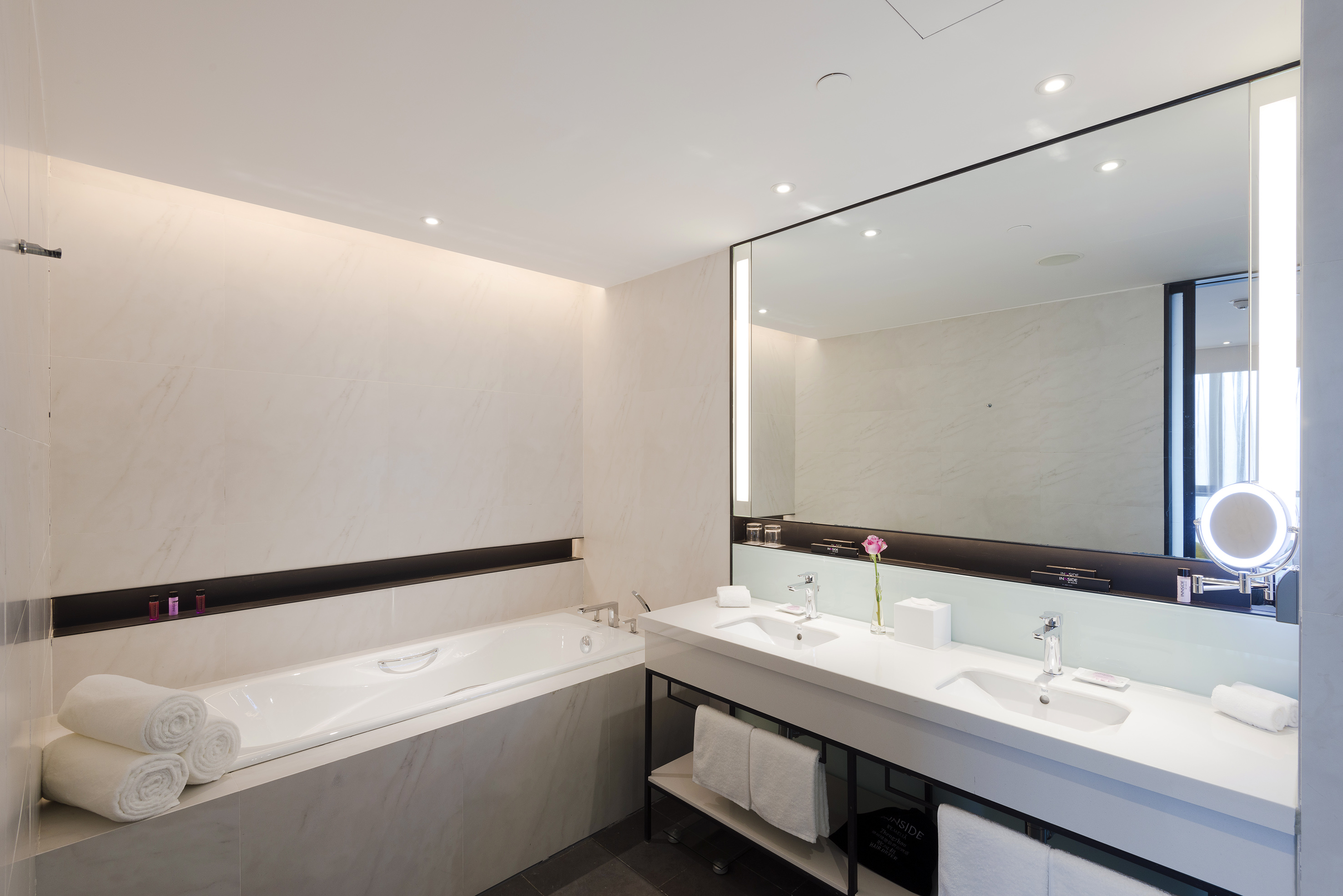 Modern luxury hotel bathroom with bathtub, double vanity, and large mirror.