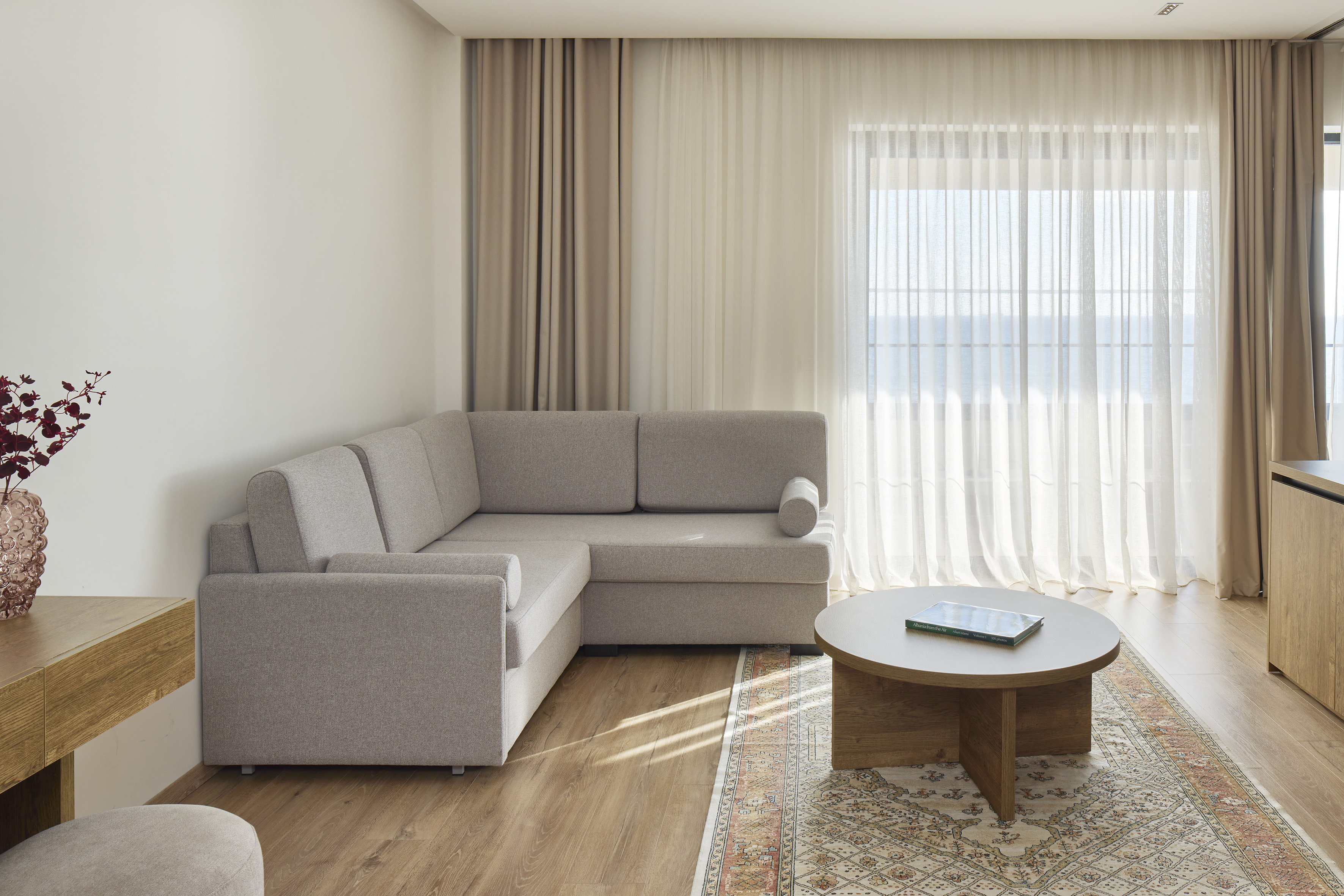 Modern living room with gray sectional sofa, coffee table, and bright sea view.