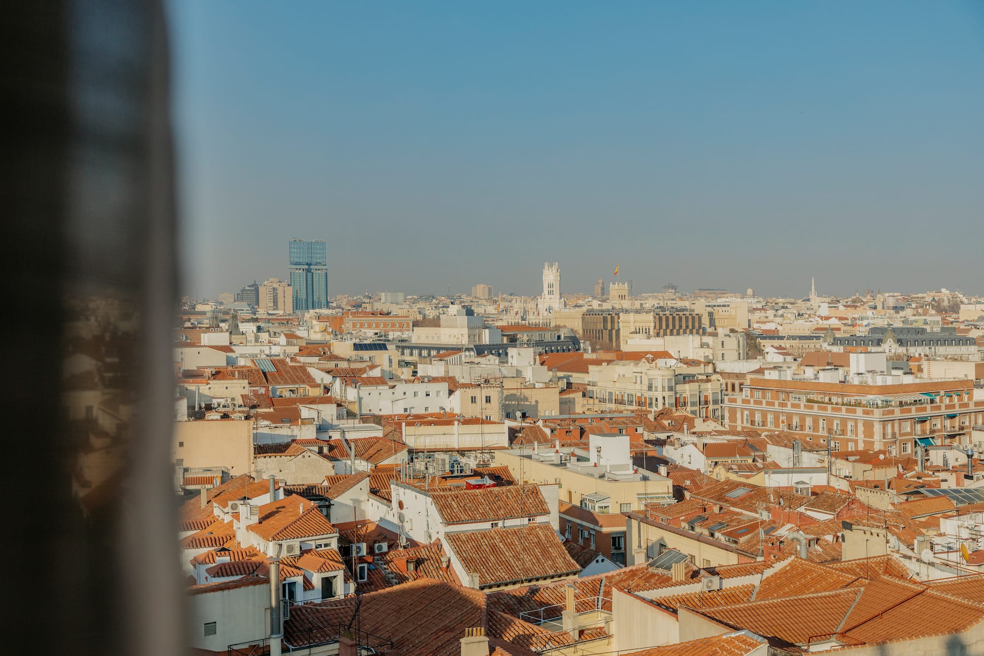 Madrid city skyline aerial view with red tiled rooftops, historic and modern buildings.