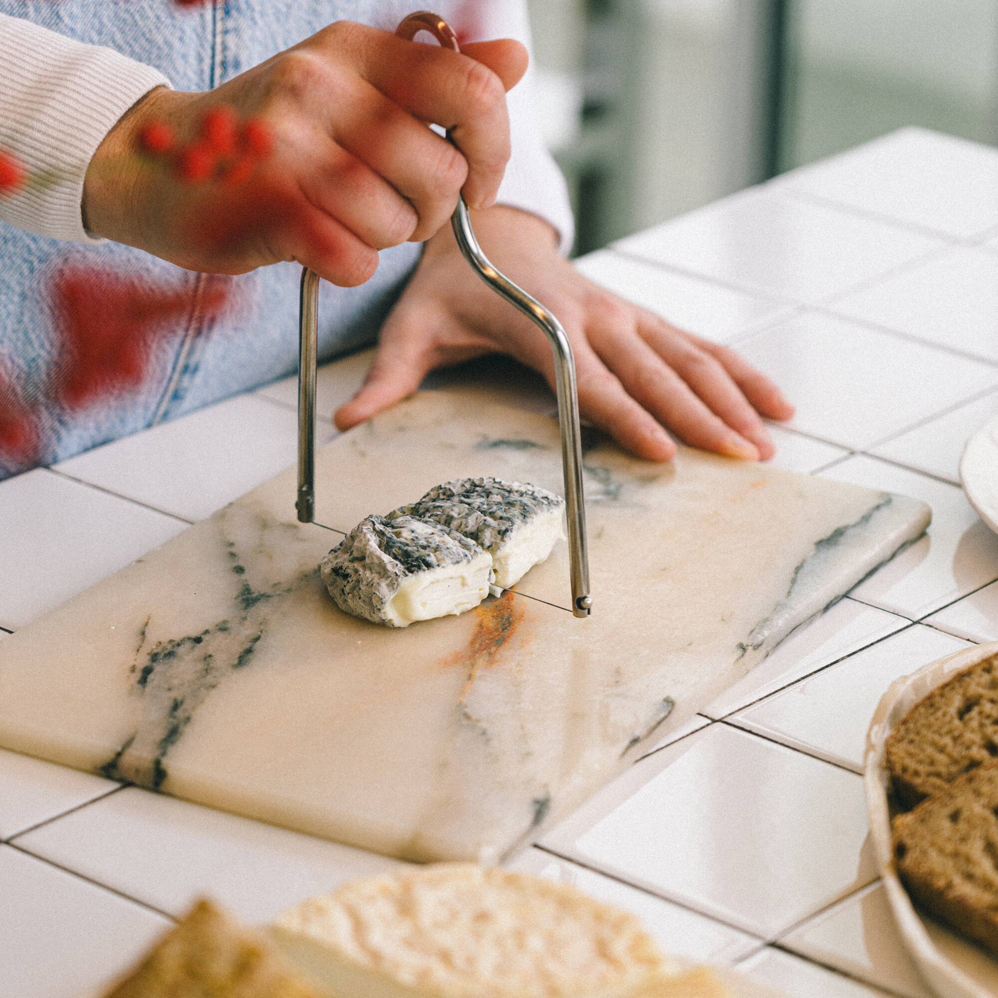 a person cutting a piece of cheese