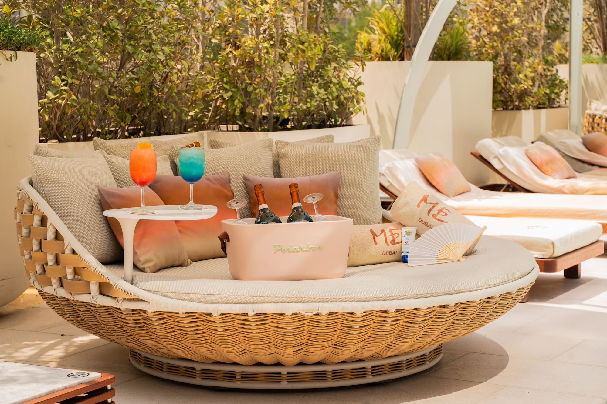 Luxury outdoor daybed with cocktails, champagne, and 'ME Dubai' details.