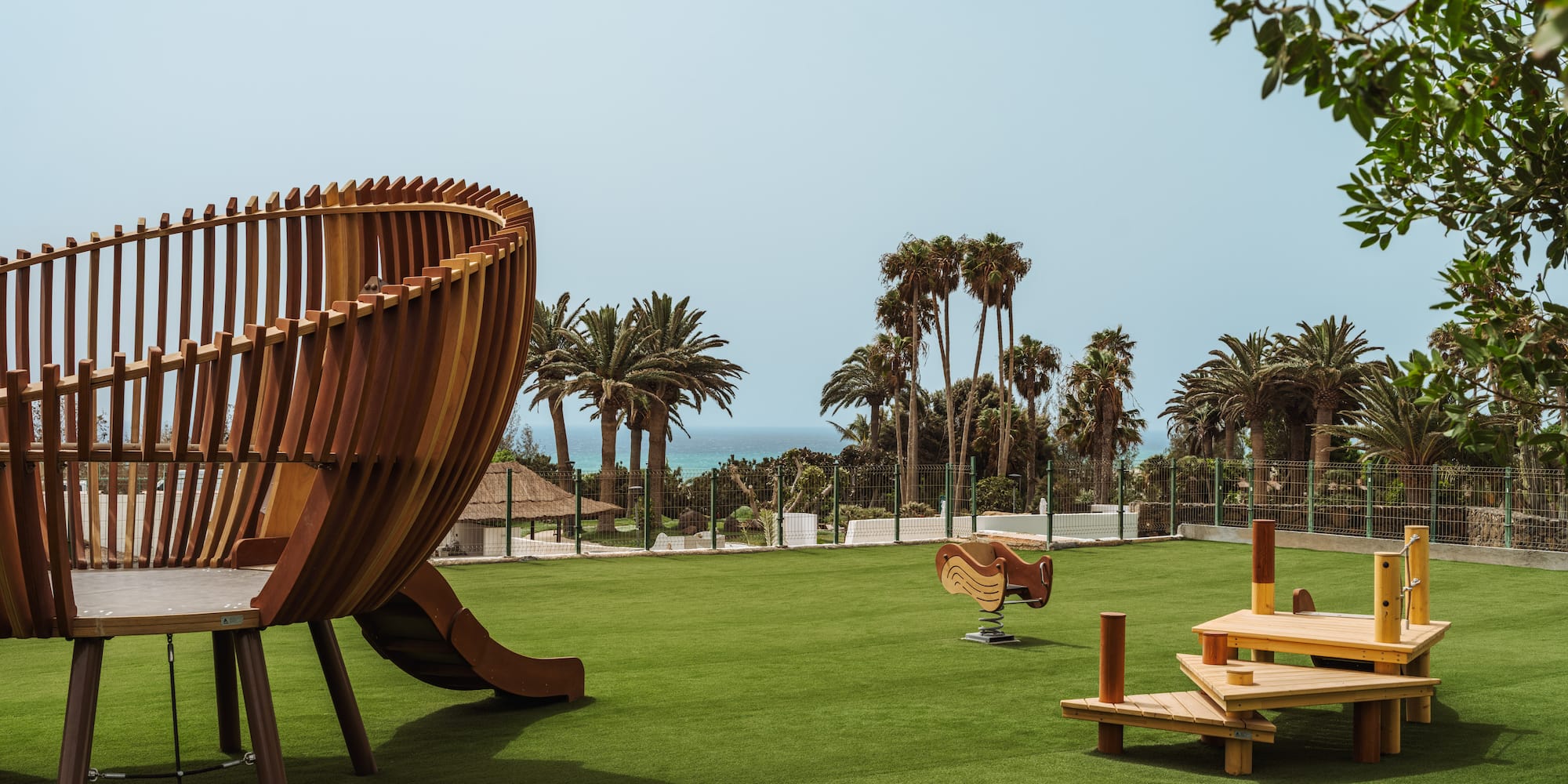 a playground with a slide and benches on a grassy field