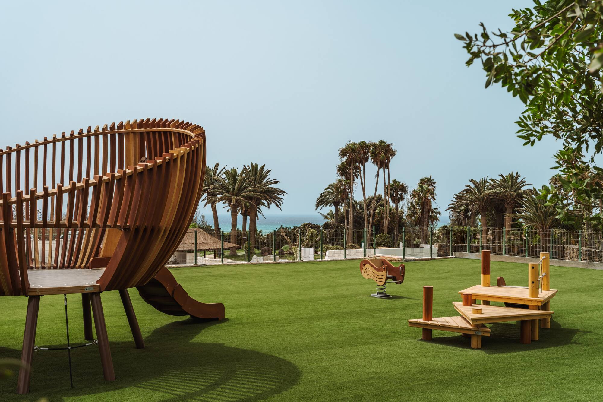 a playground with a slide and benches on a grassy field