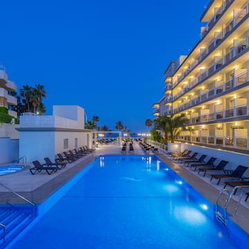 a pool with chairs and a building with palm trees