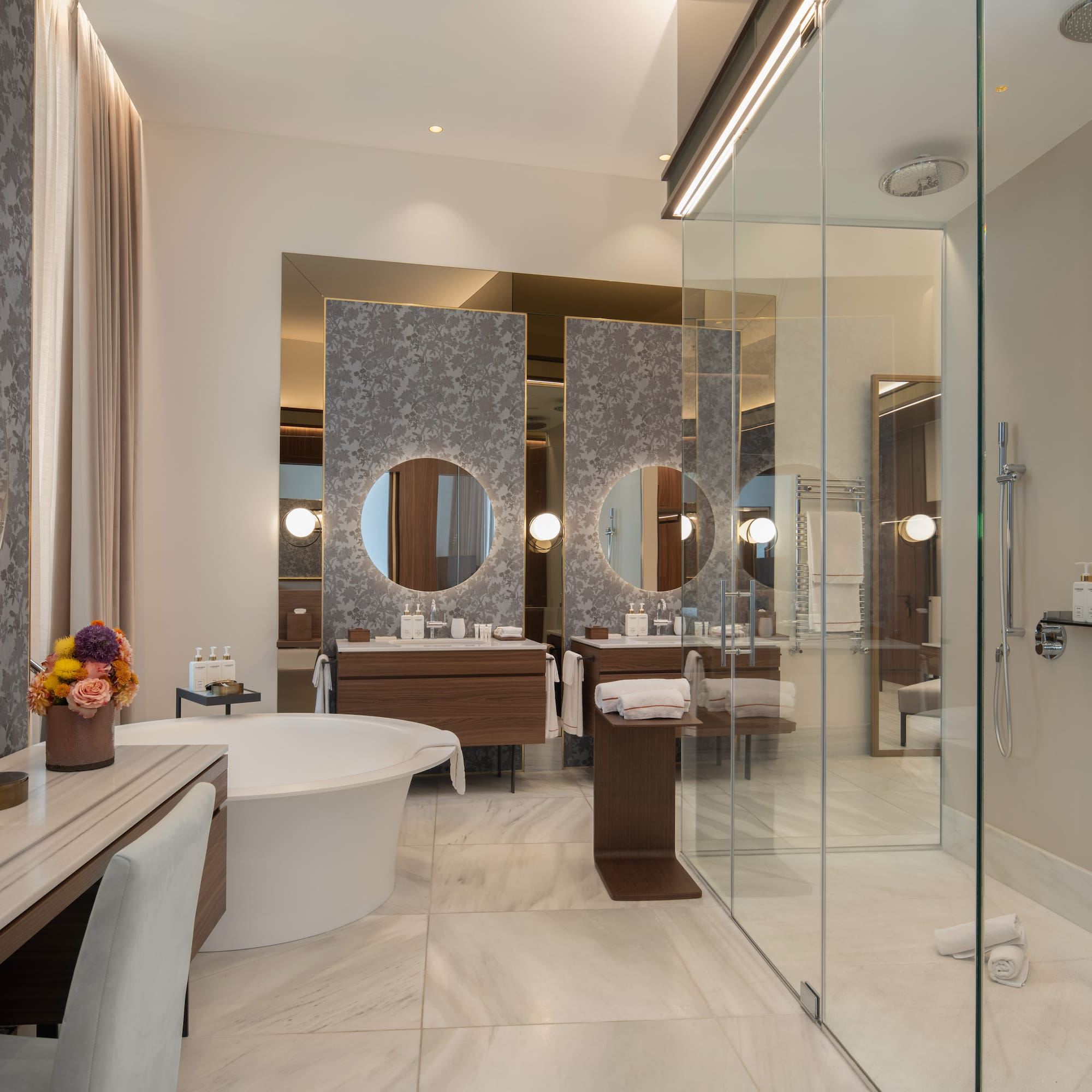 Modern luxury bathroom with freestanding tub, double vanity, and glass shower.