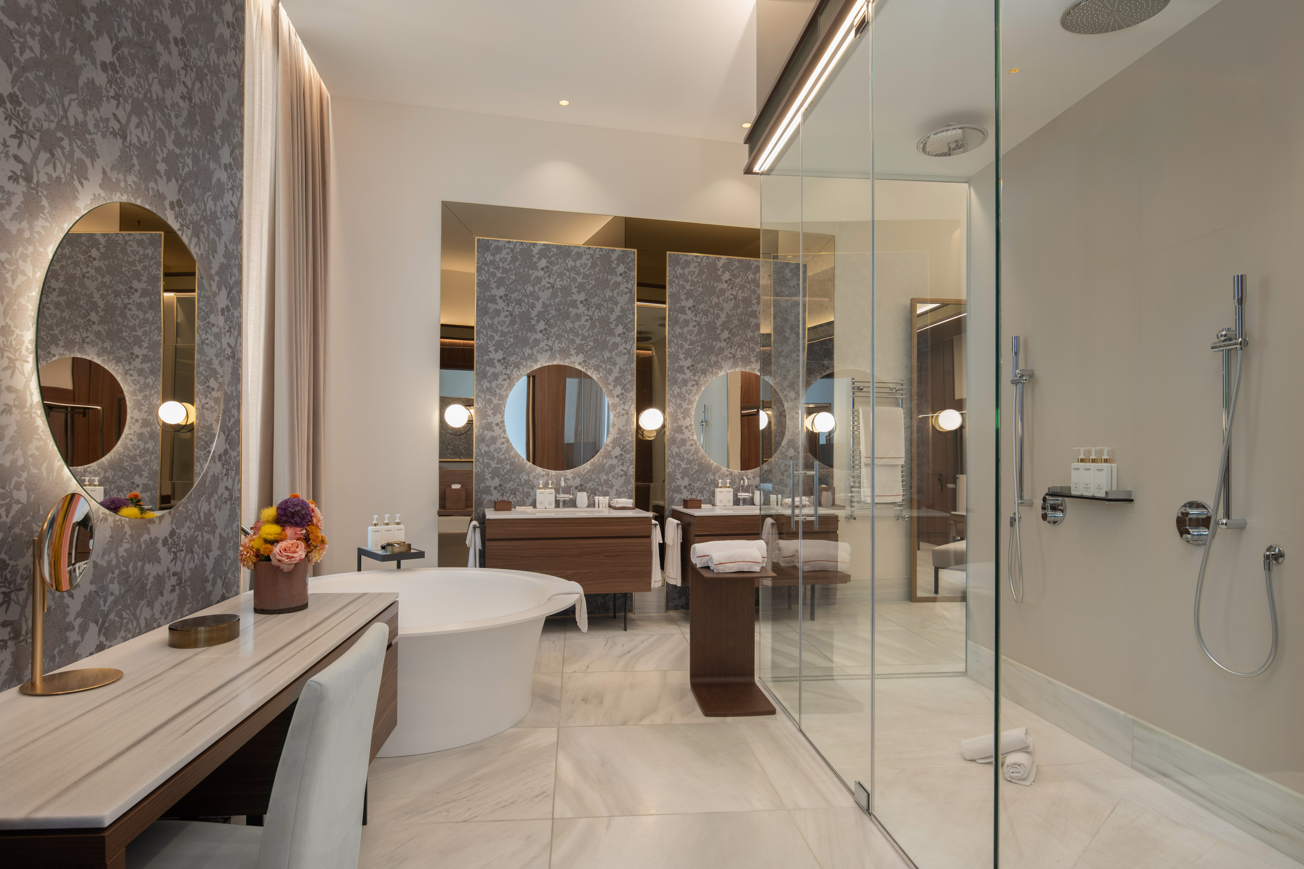 Modern luxury bathroom with freestanding tub, double vanity, and glass shower.