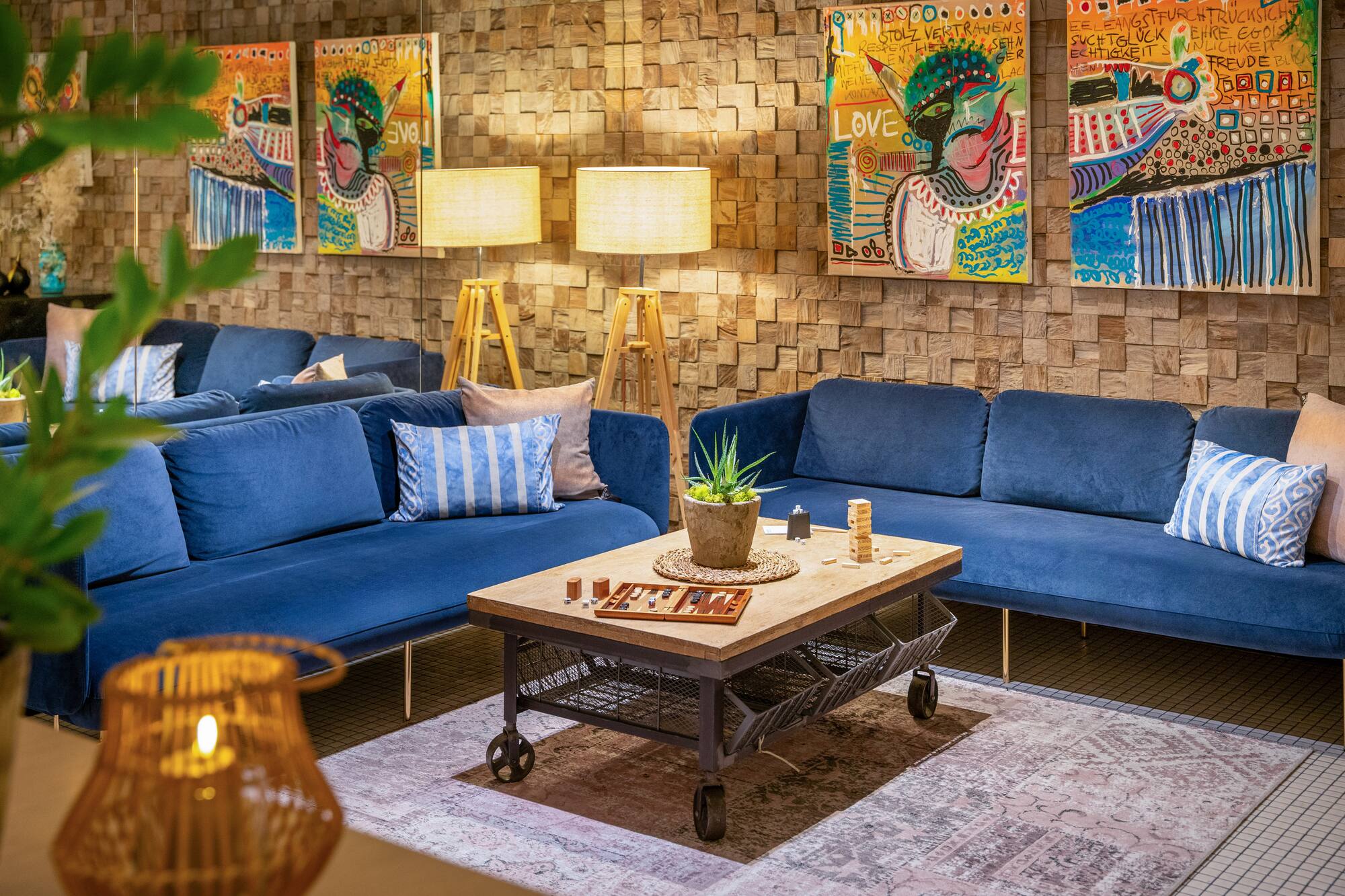 Blue velvet sofas, wood coffee table, abstract art on wood block wall.