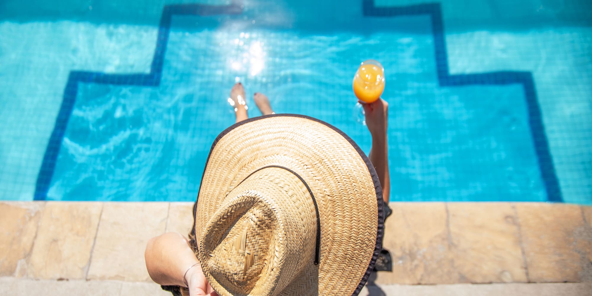 a woman sitting by a pool with a drink