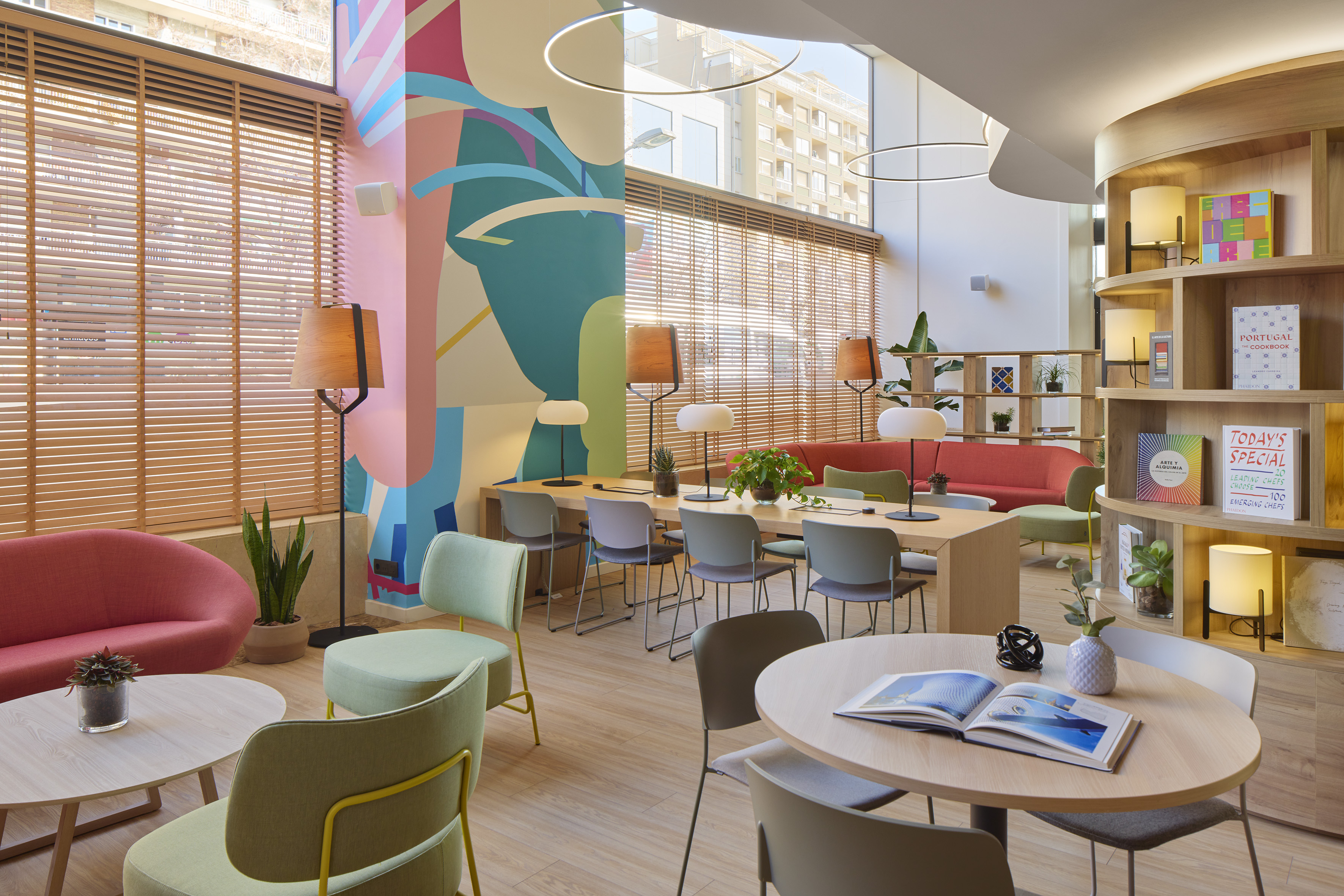 Vibrant modern lobby with colorful mural, co-working table, and lounge seating.