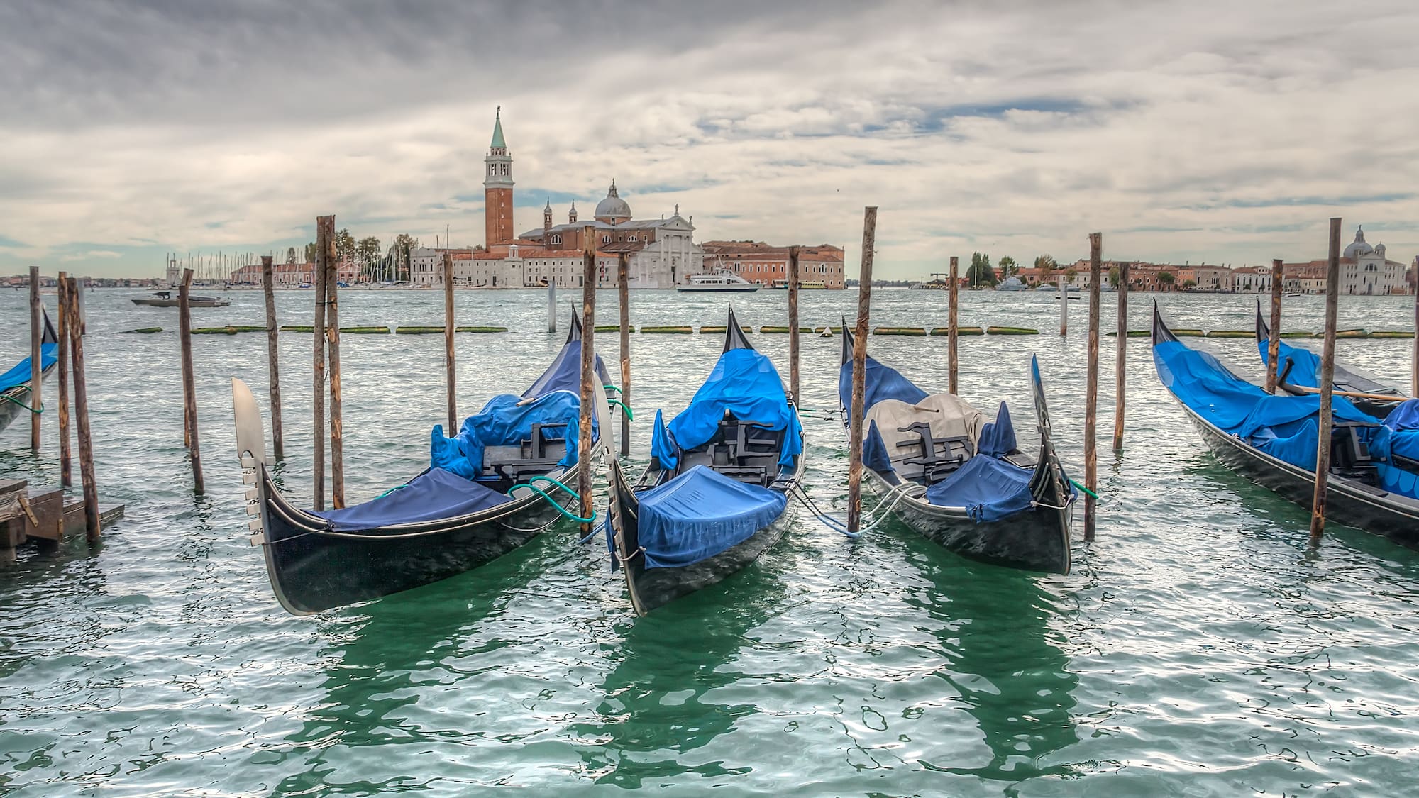 a row of boats in water with blue covers