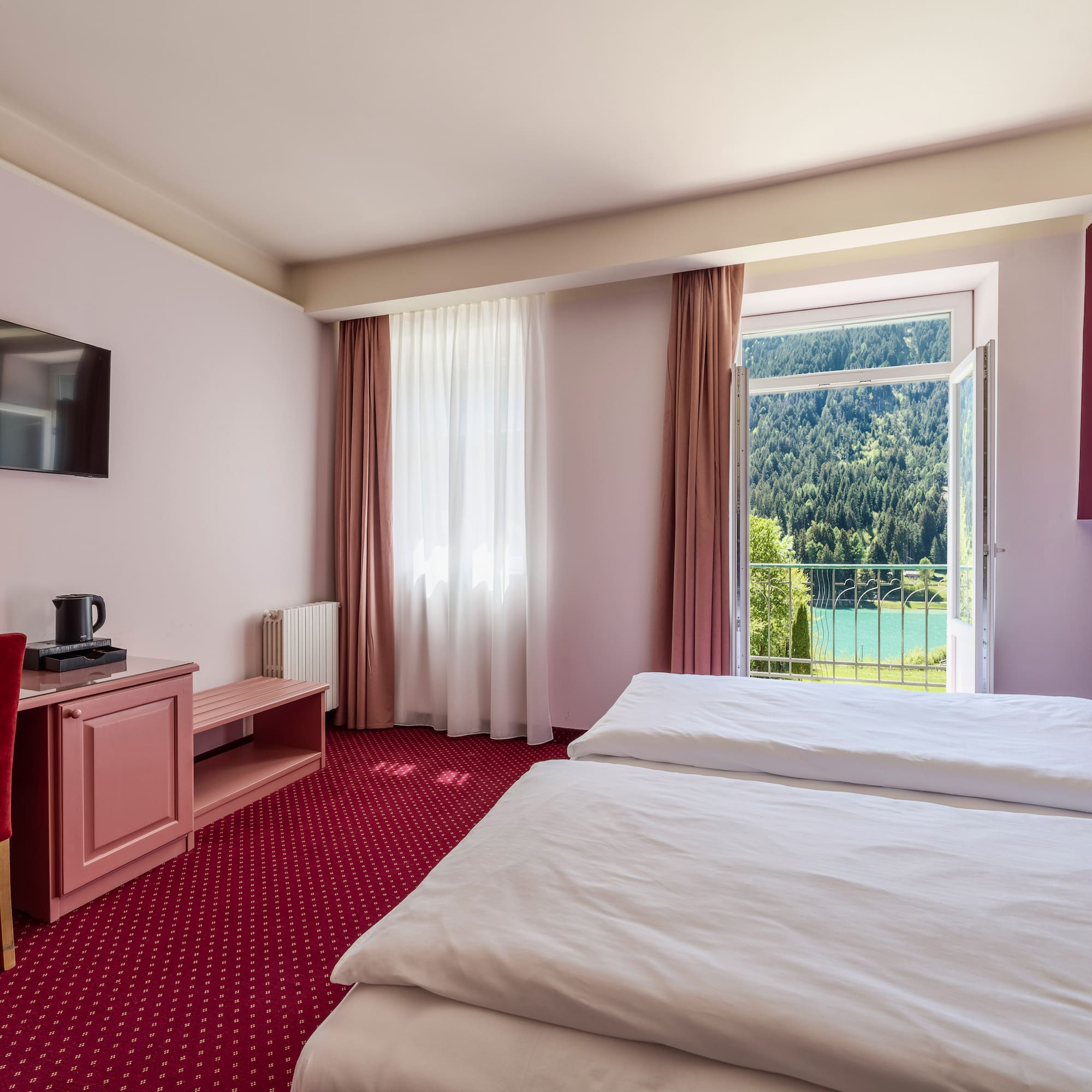 Hotel room, twin beds, desk, balcony with scenic lake and mountain view.