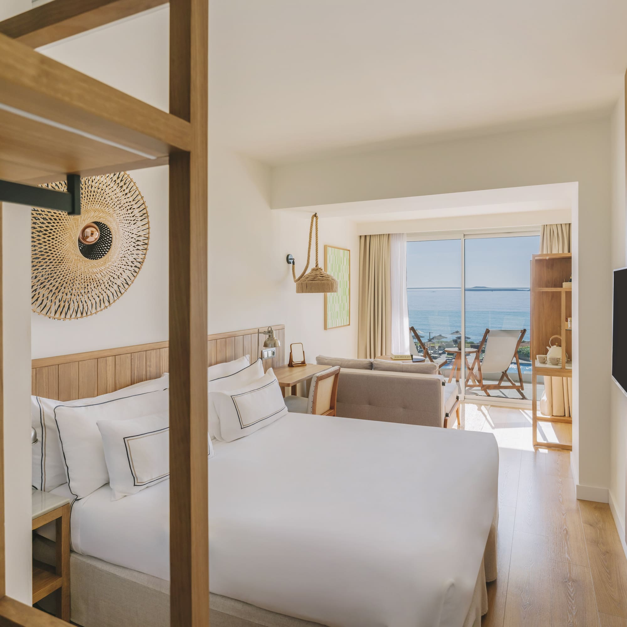 Modern hotel room with king bed, ocean view balcony, and wood decor.