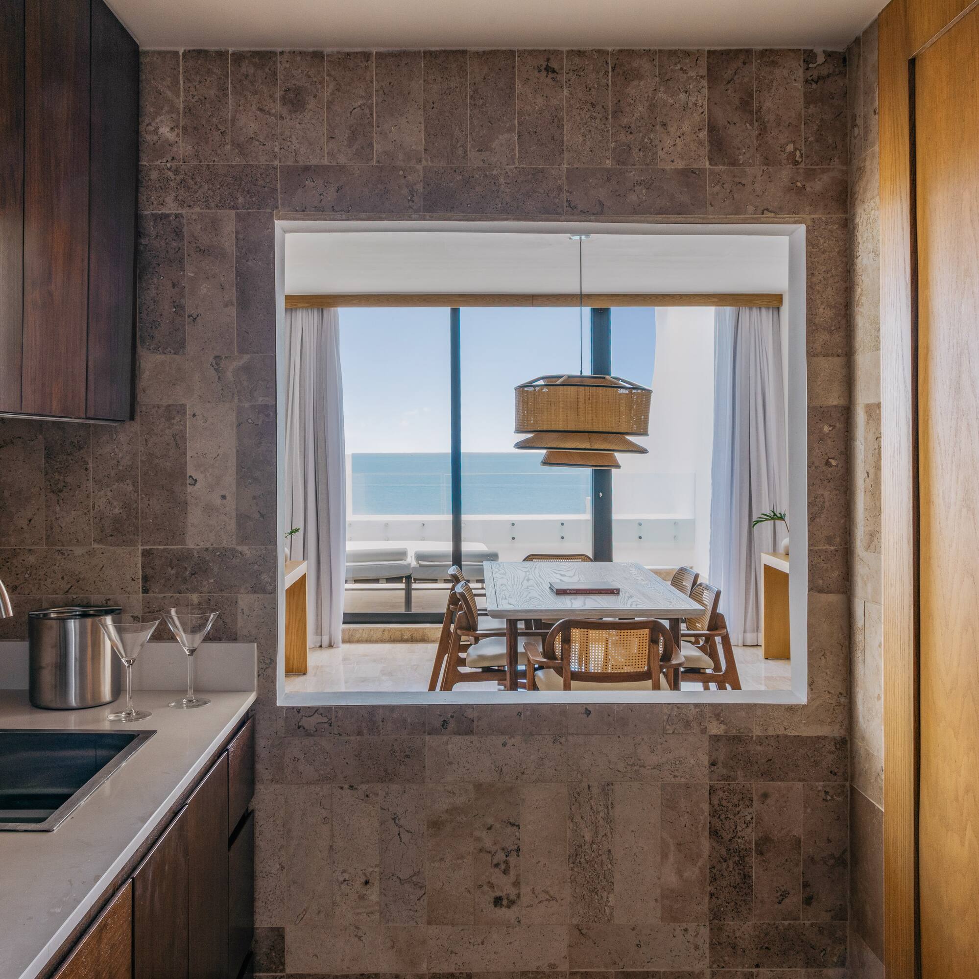 Modern kitchen with sink, ocean view dining room, wood and stone.