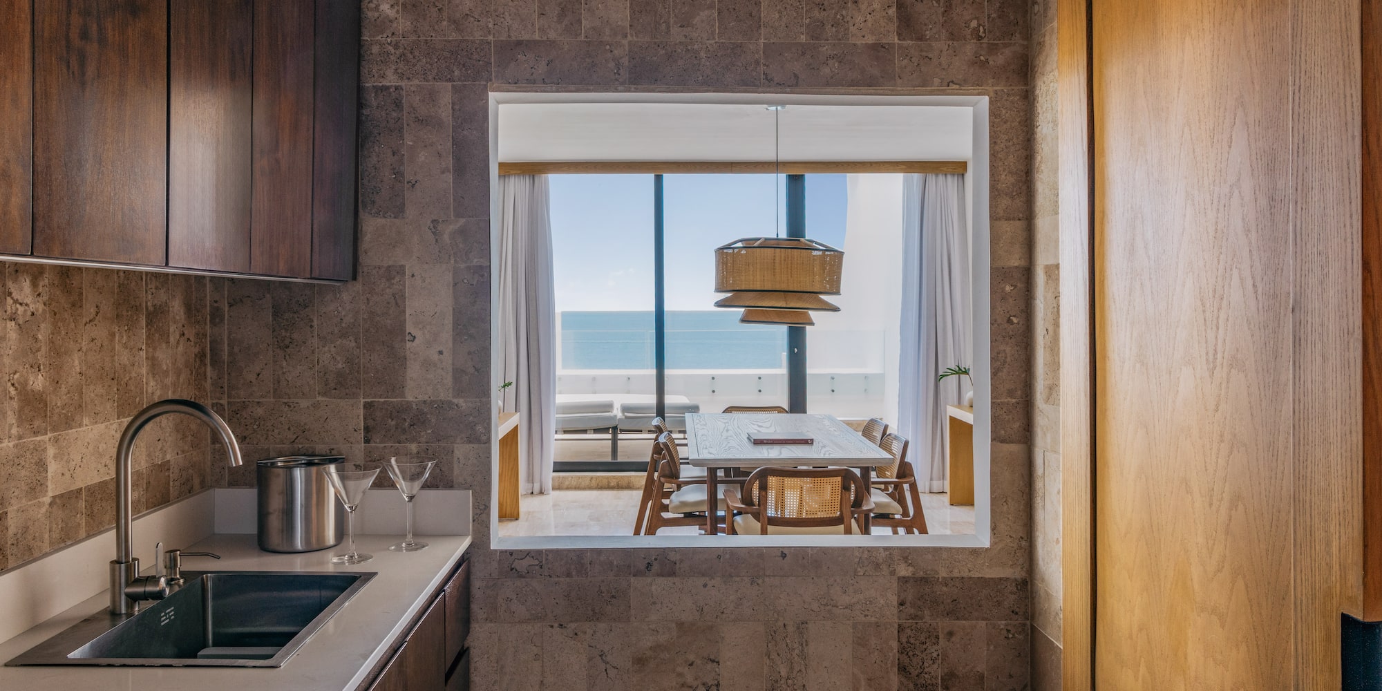 Modern kitchen with sink, ocean view dining room, wood and stone.