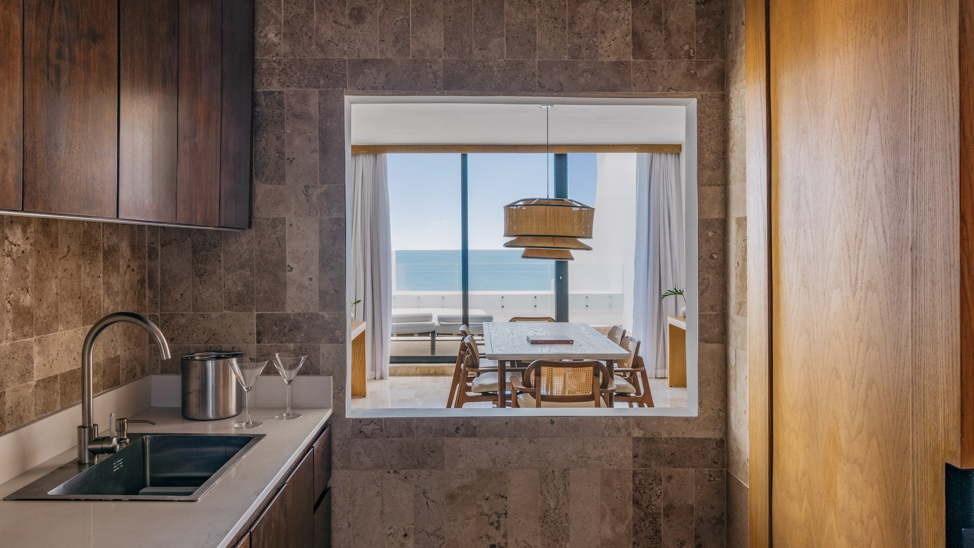 Modern kitchen with sink, ocean view dining room, wood and stone.