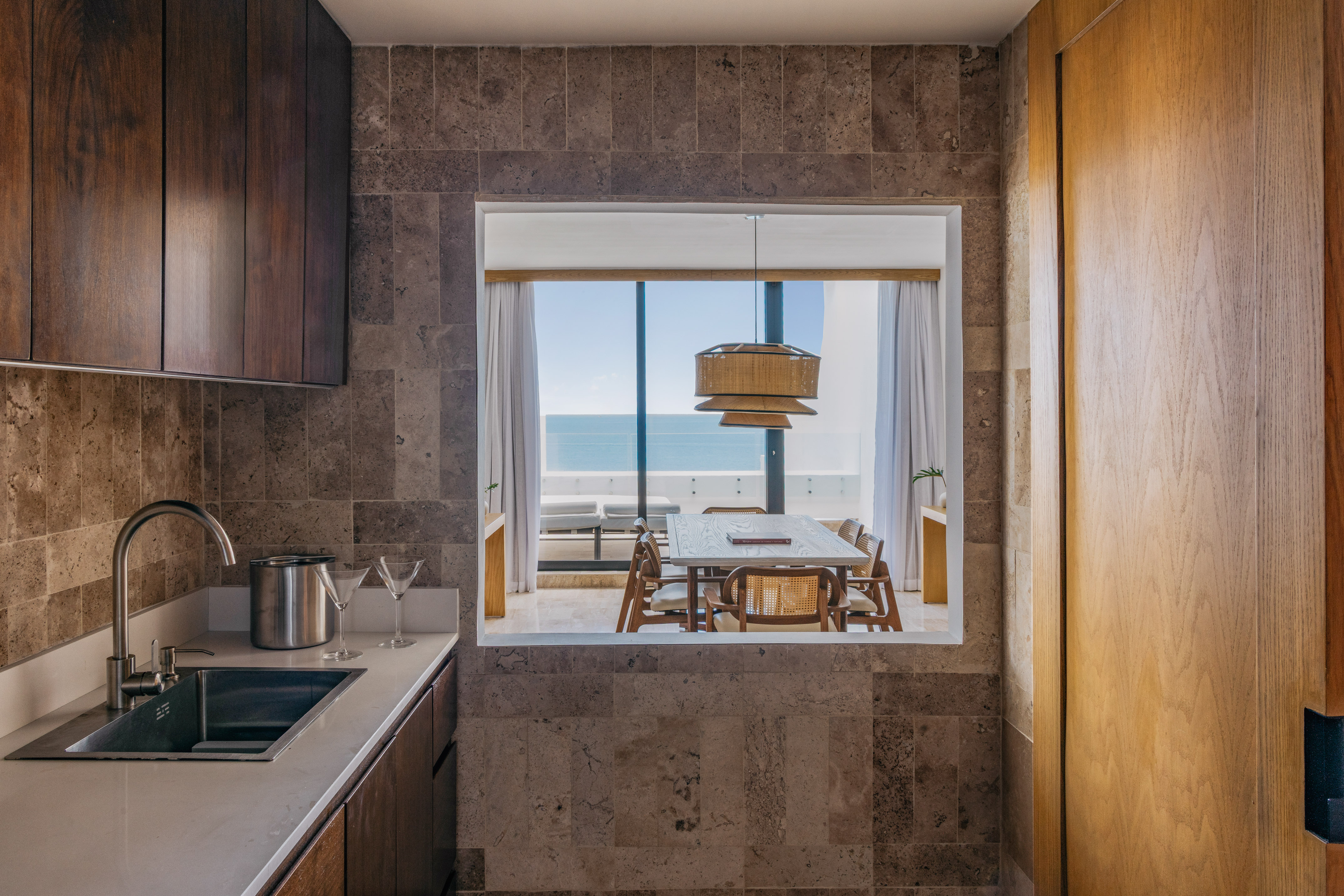 Modern kitchen with sink, ocean view dining room, wood and stone.