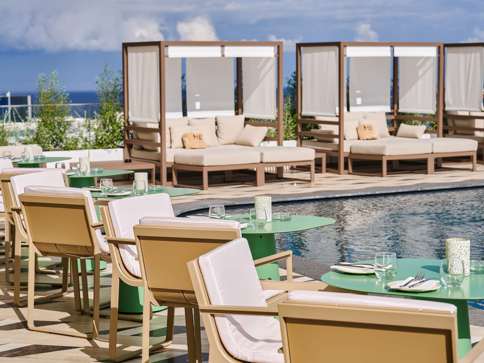 Luxury poolside dining and lounge area with ocean view daybeds.