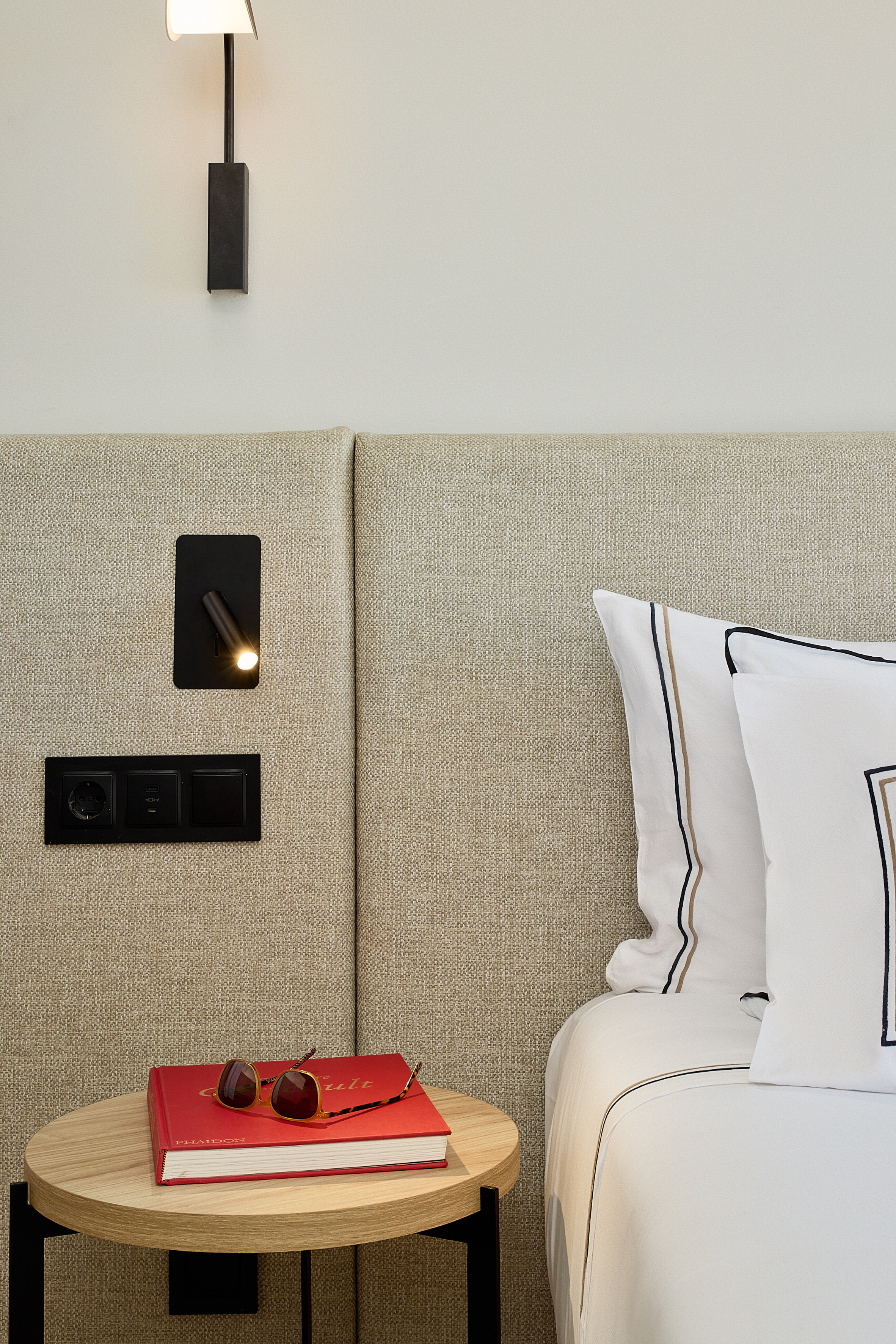 Modern bedroom design: upholstered headboard, wooden nightstand, reading light.