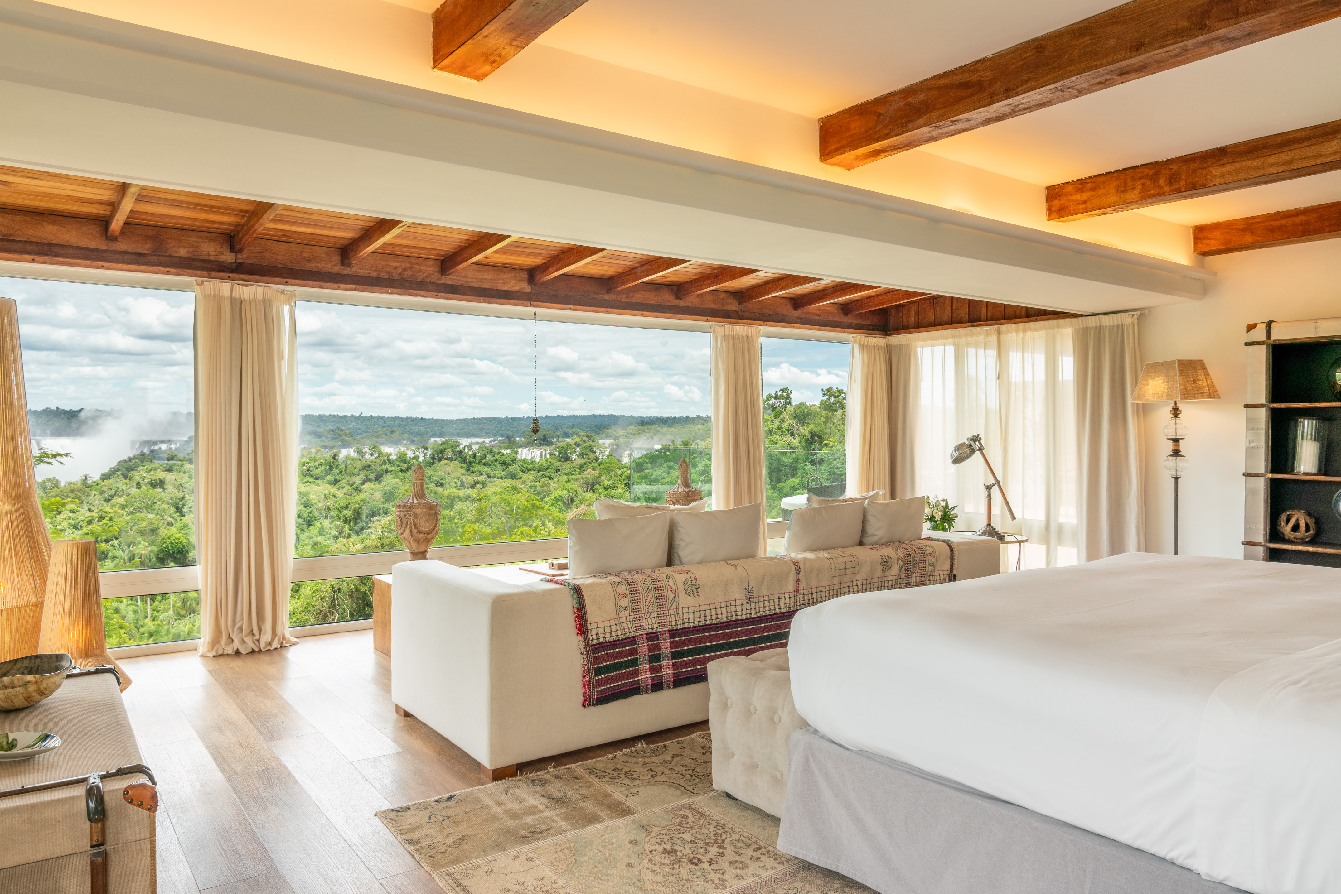 Luxury suite with panoramic windows overlooking Iguazu Falls and jungle.