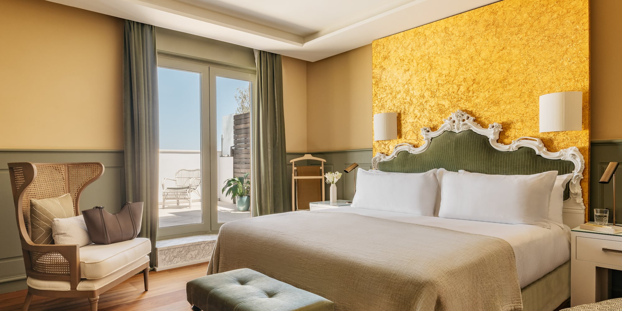 Lujosa suite de hotel con cama, cabecero verde, pared dorada y balcón.