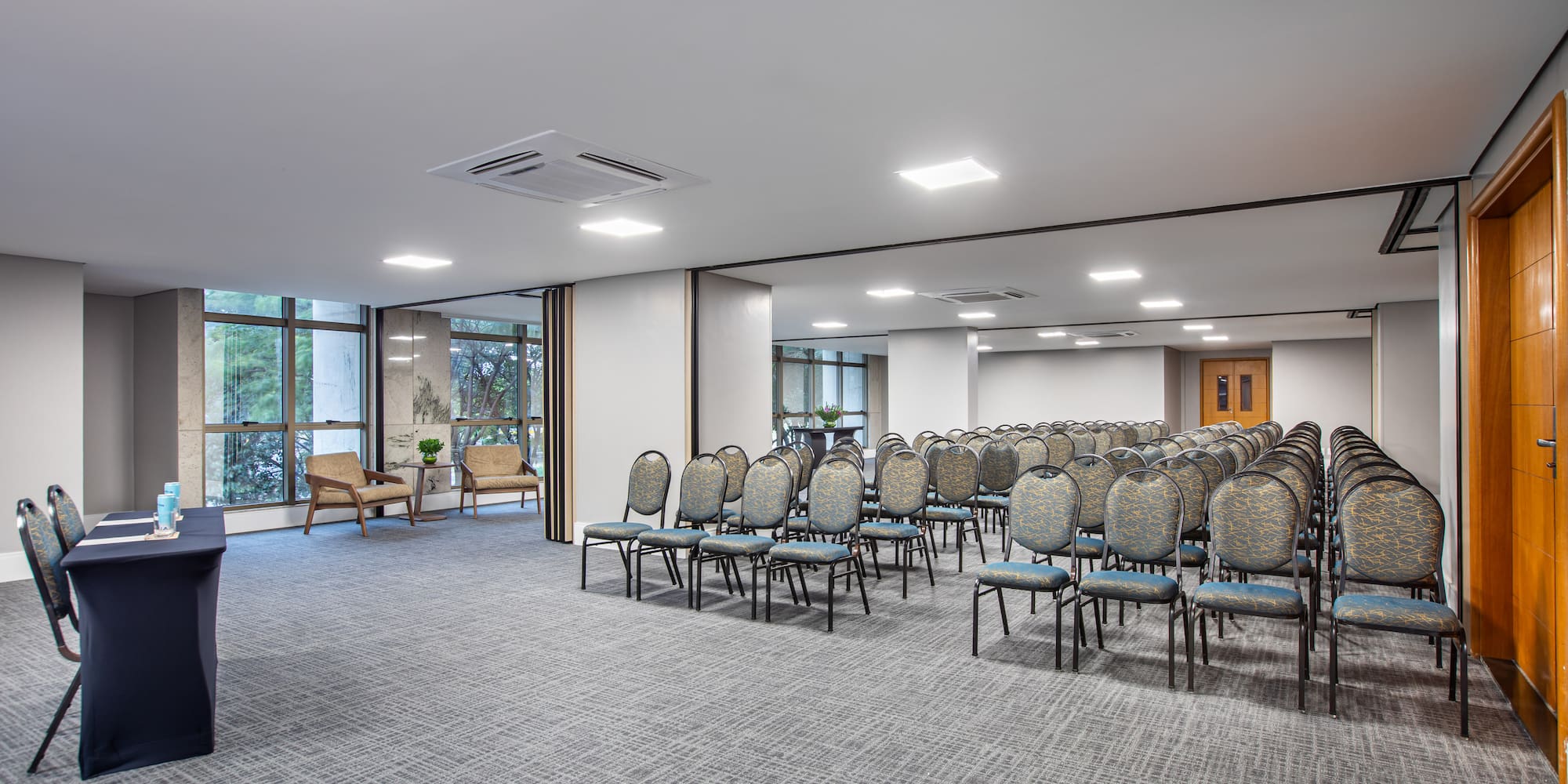 Conference room with rows of empty chairs, small table, and large windows.