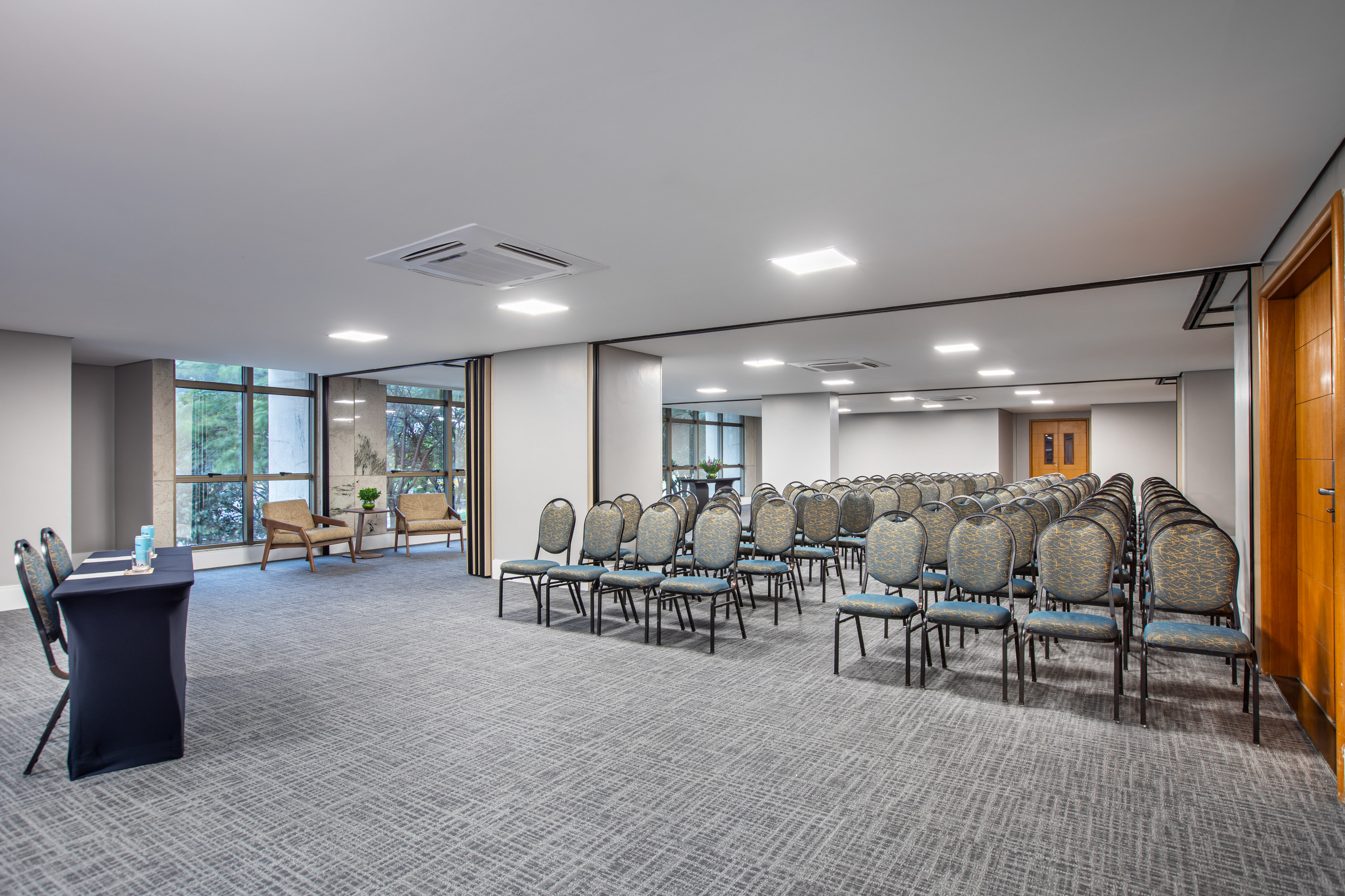 Conference room with rows of empty chairs, small table, and large windows.
