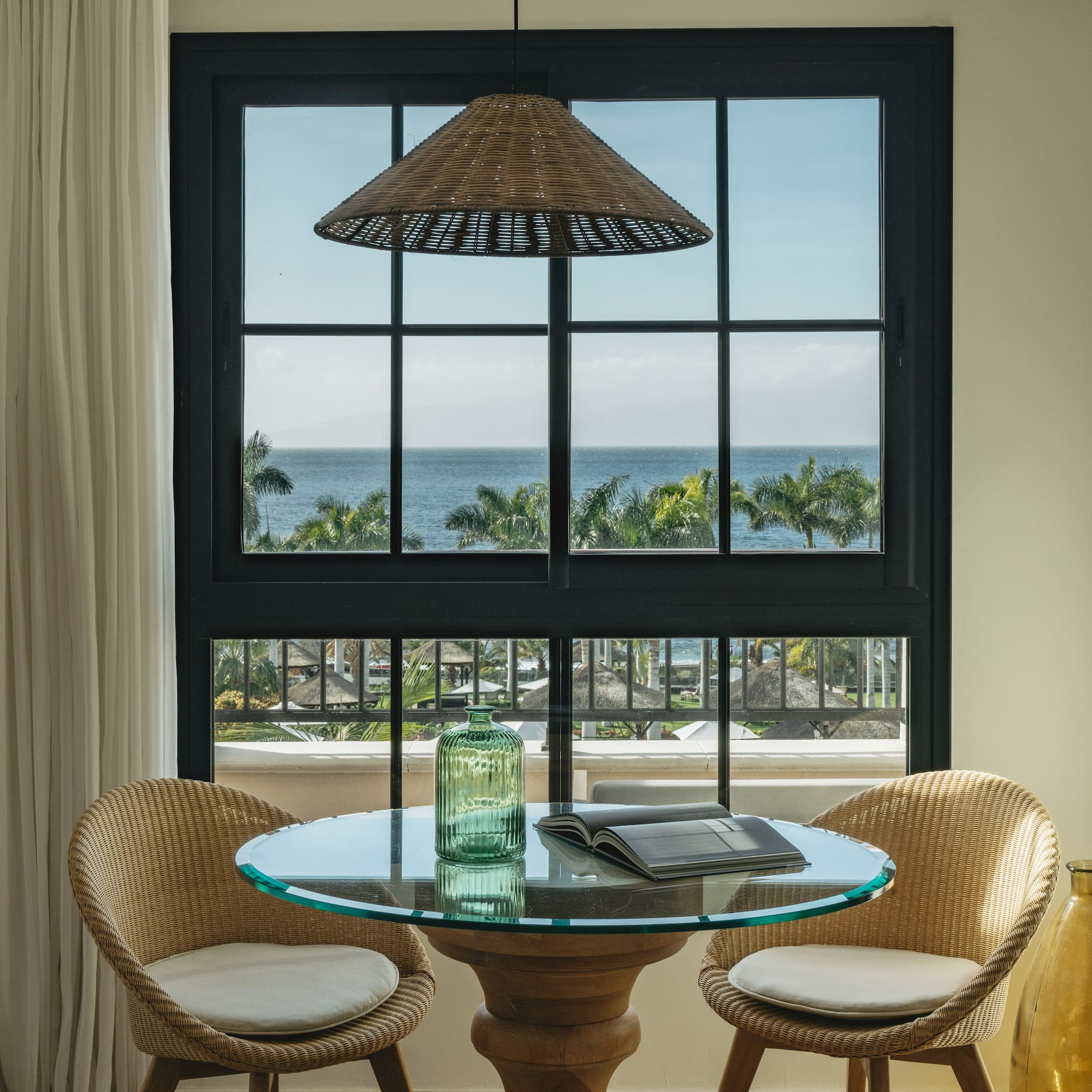 a table with chairs in a room with a view of the ocean