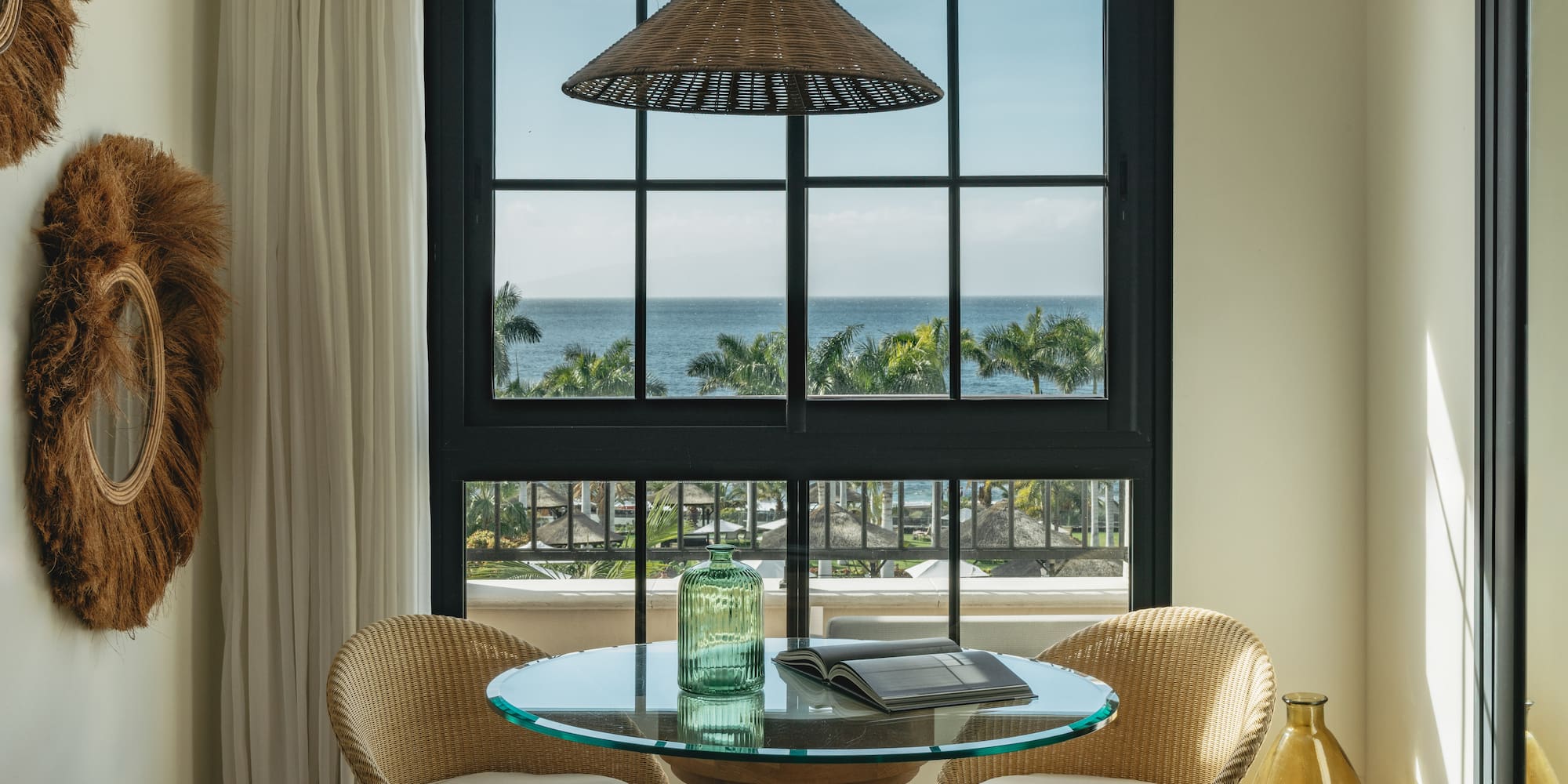 a table with chairs in a room with a view of the ocean