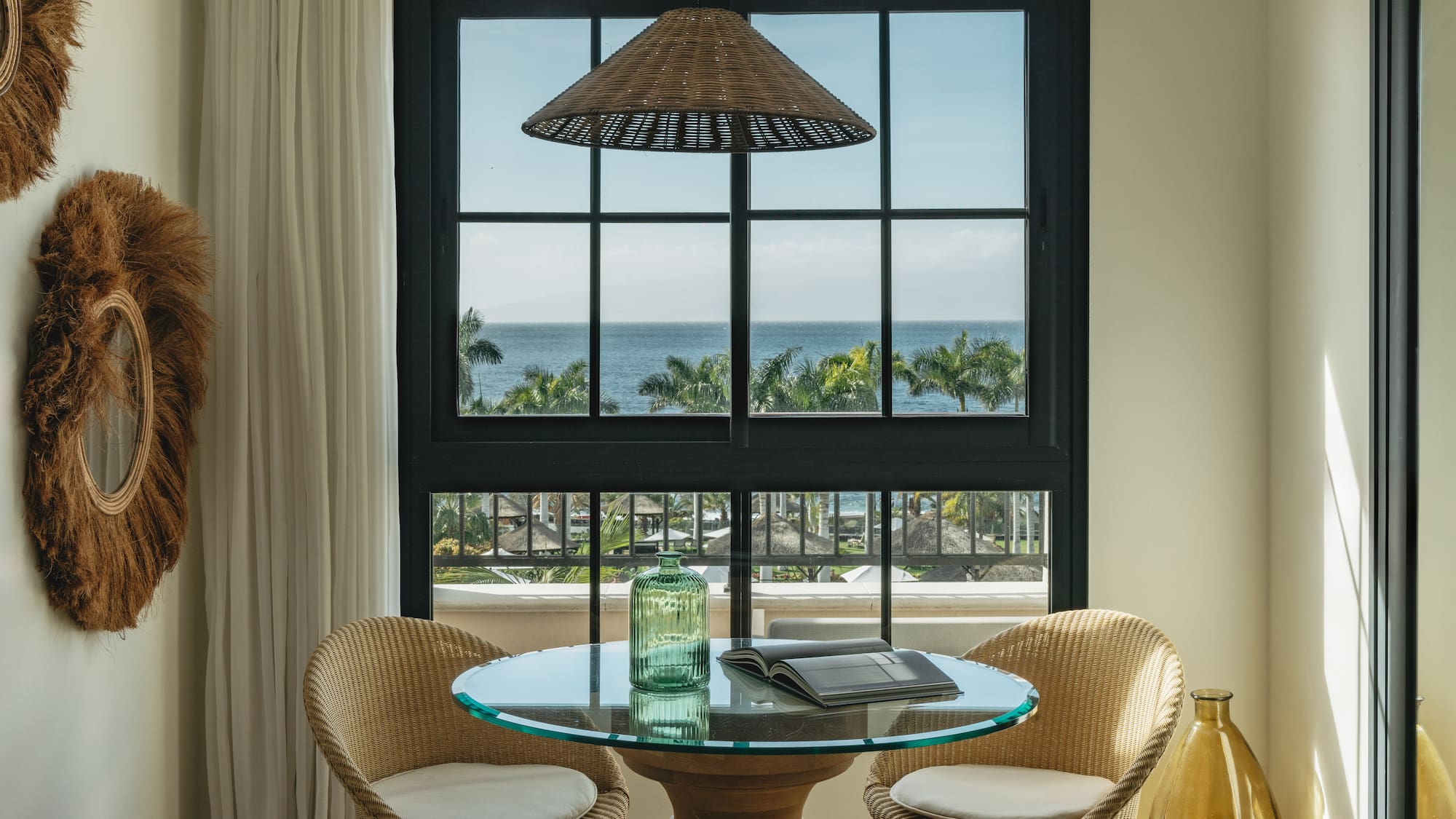 a table with chairs in a room with a view of the ocean