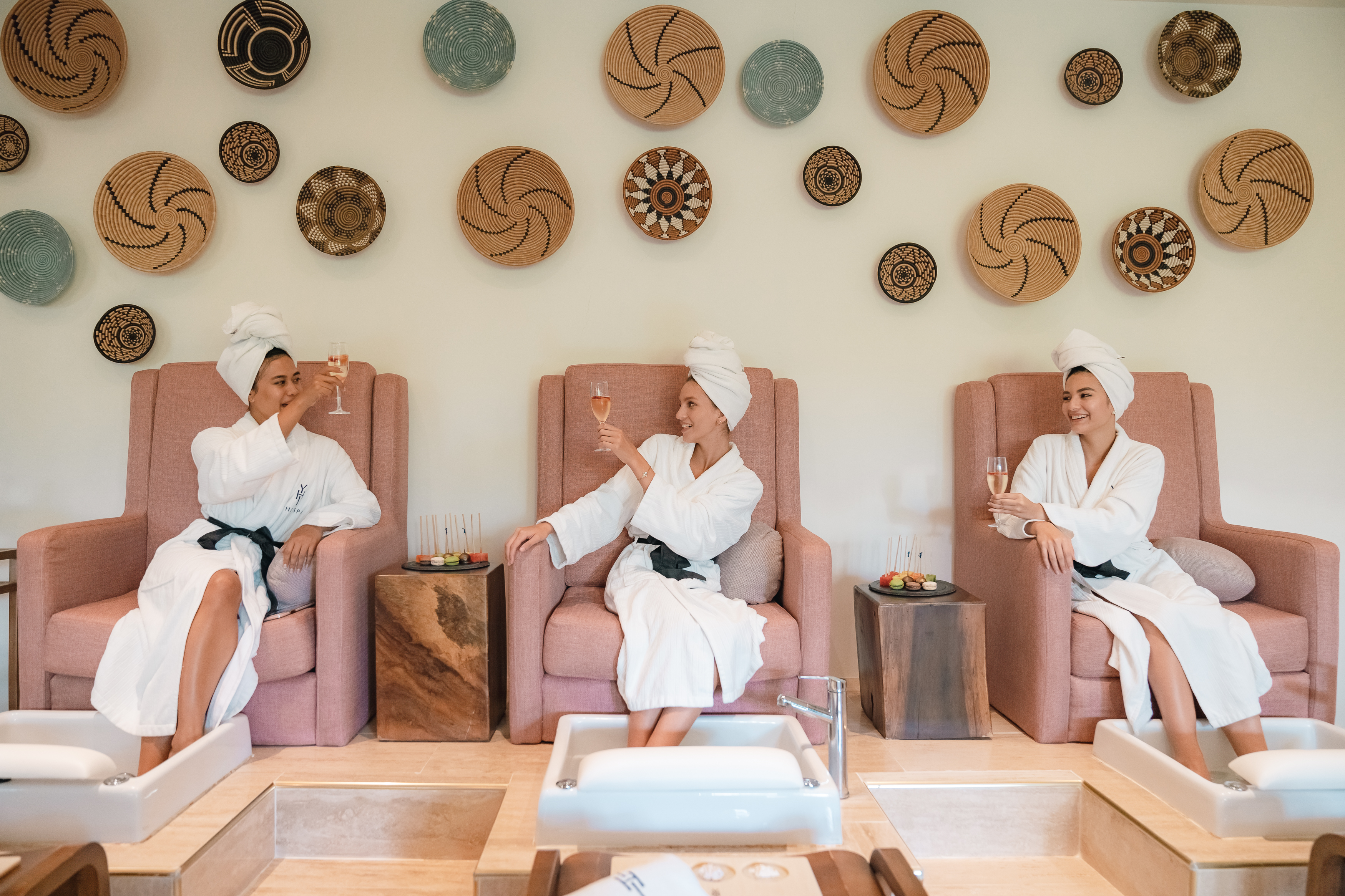 a group of women in white robes sitting in chairs with drinks