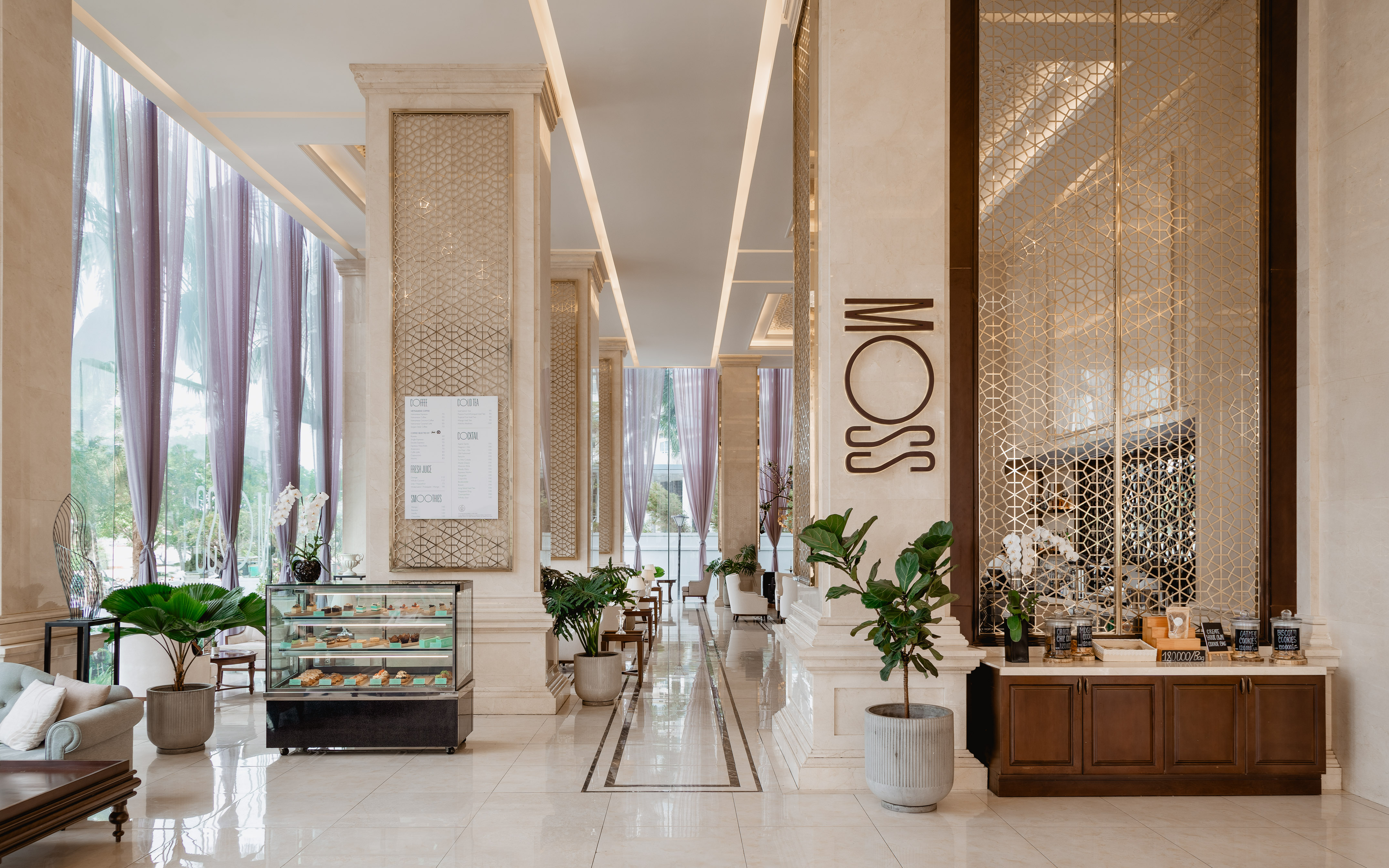 Upscale MOSS cafe interior with dessert case, drinks menu, and marble columns.