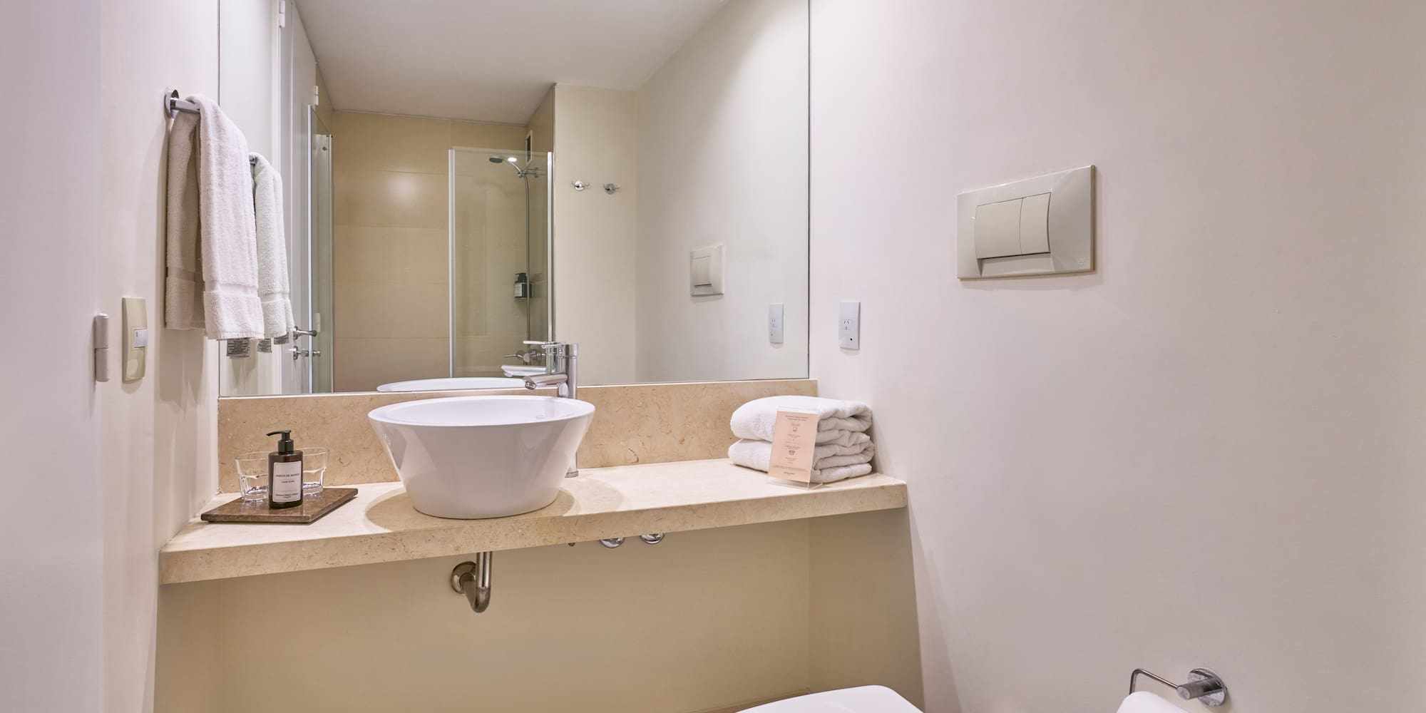 Contemporary hotel bathroom with vessel sink, large mirror, and white towels.