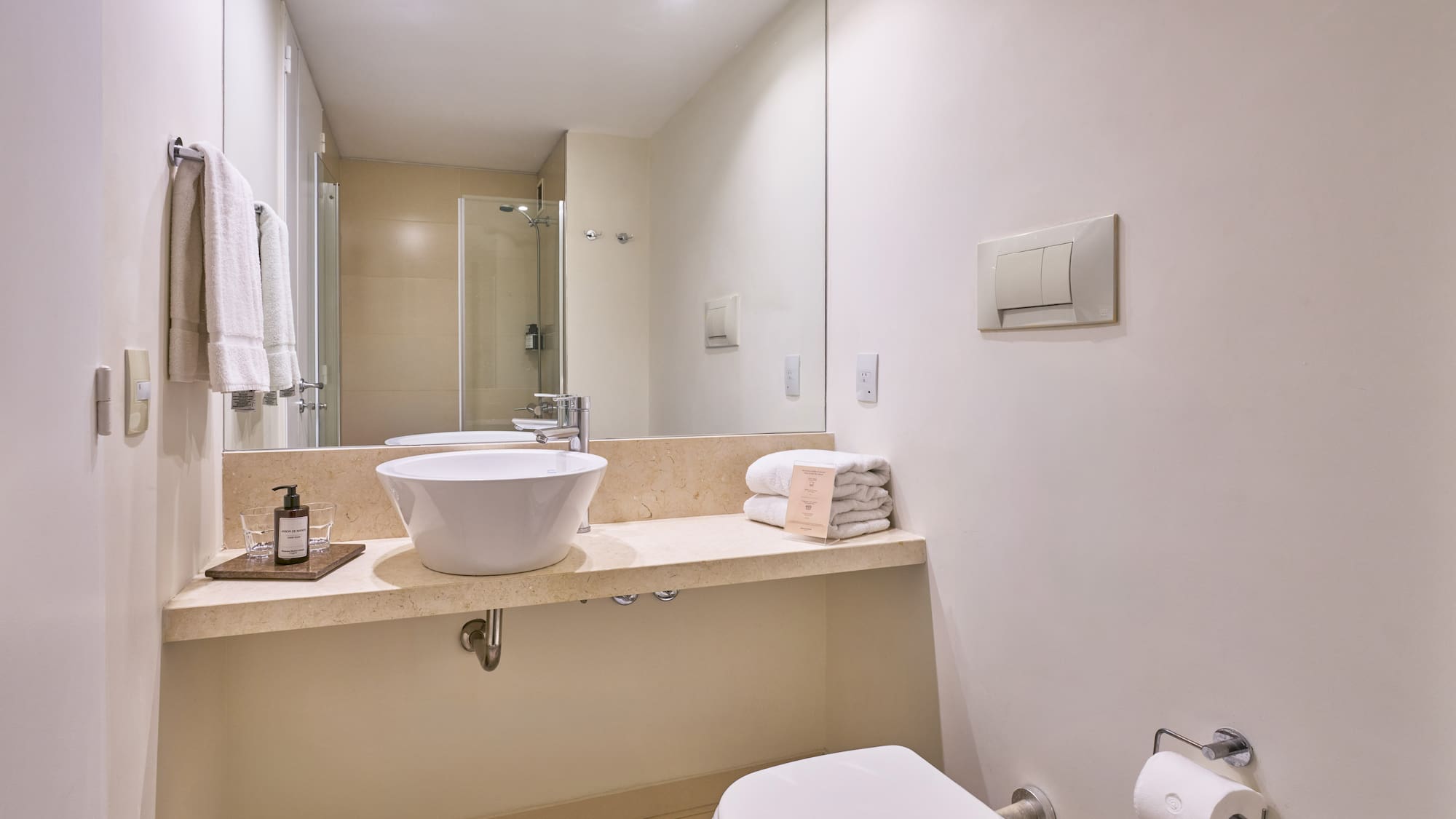 Contemporary hotel bathroom with vessel sink, large mirror, and white towels.