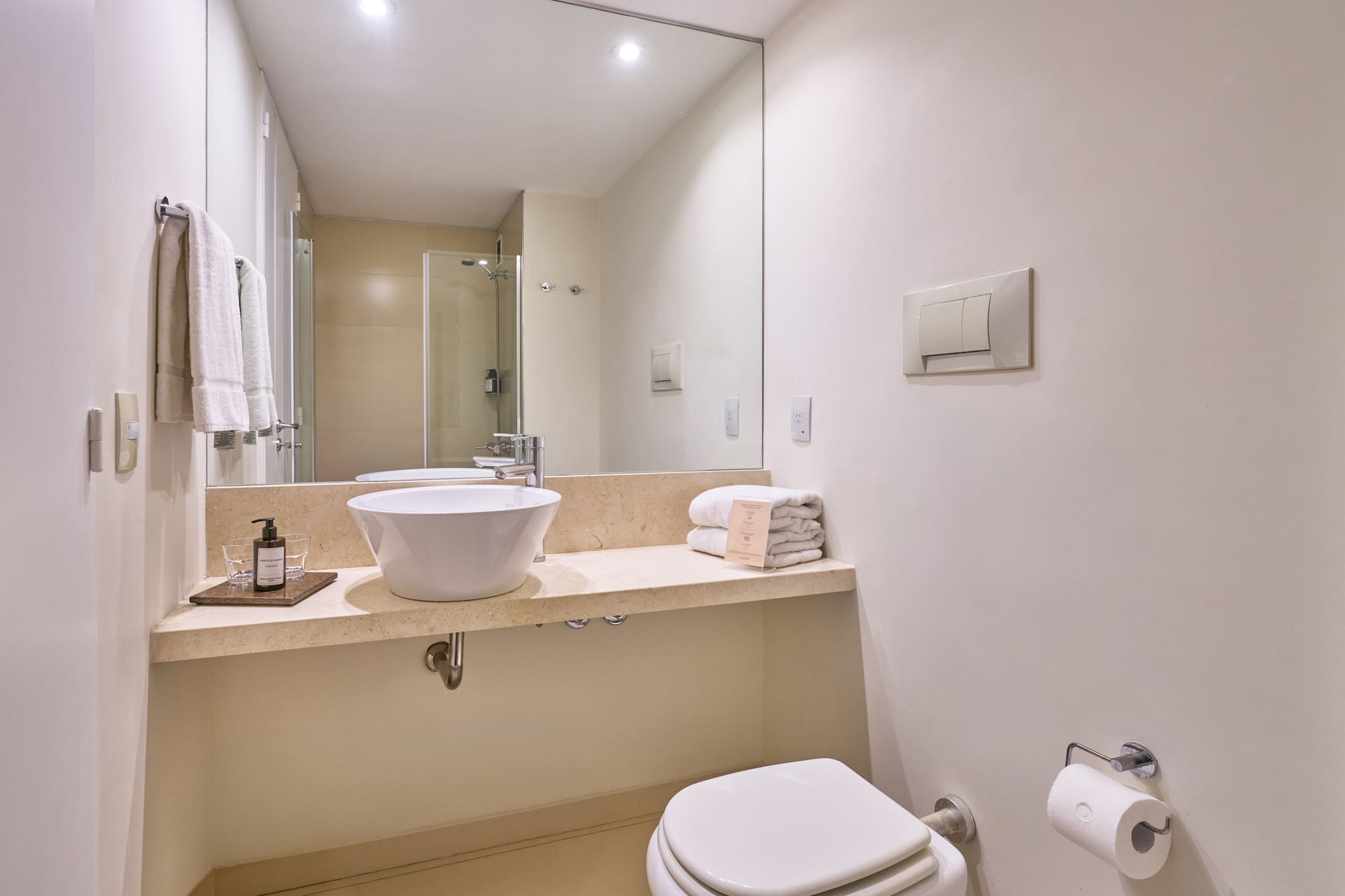 Contemporary hotel bathroom with vessel sink, large mirror, and white towels.