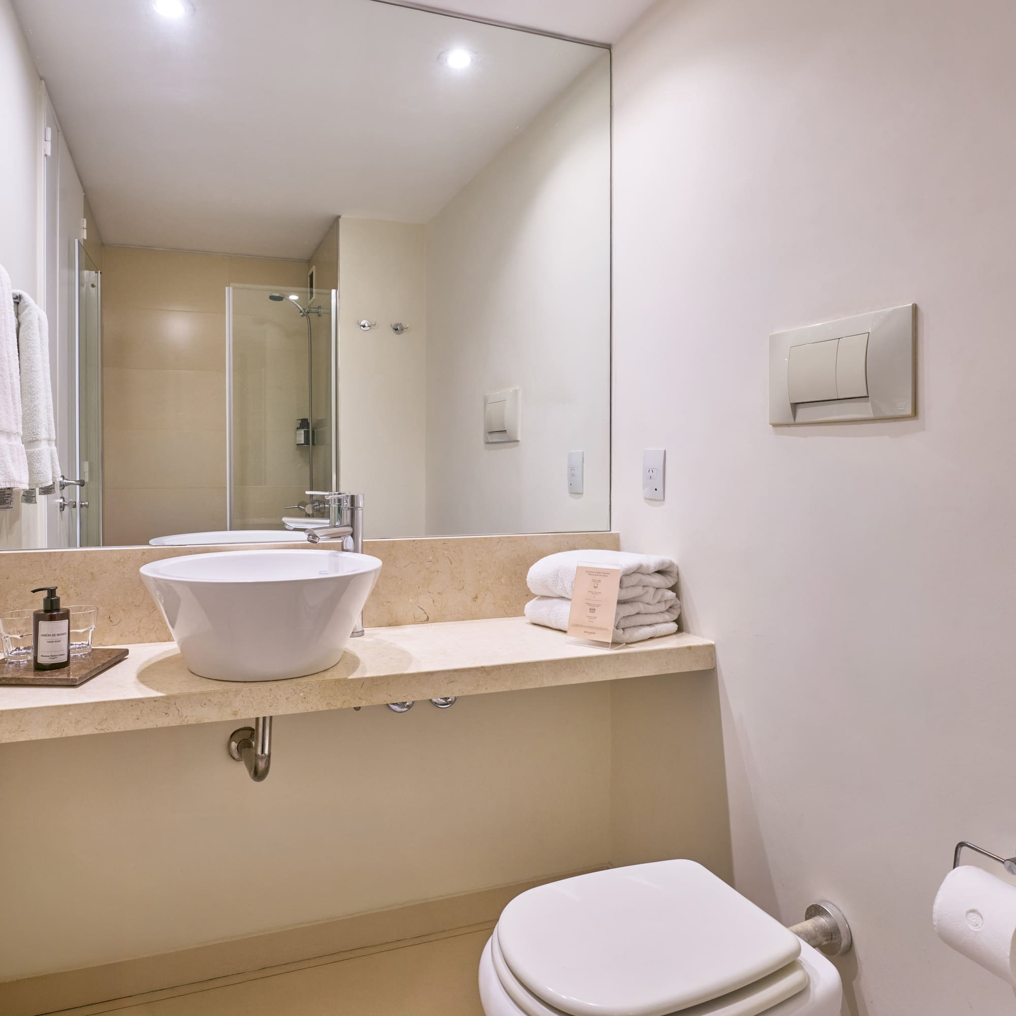 Contemporary hotel bathroom with vessel sink, large mirror, and white towels.