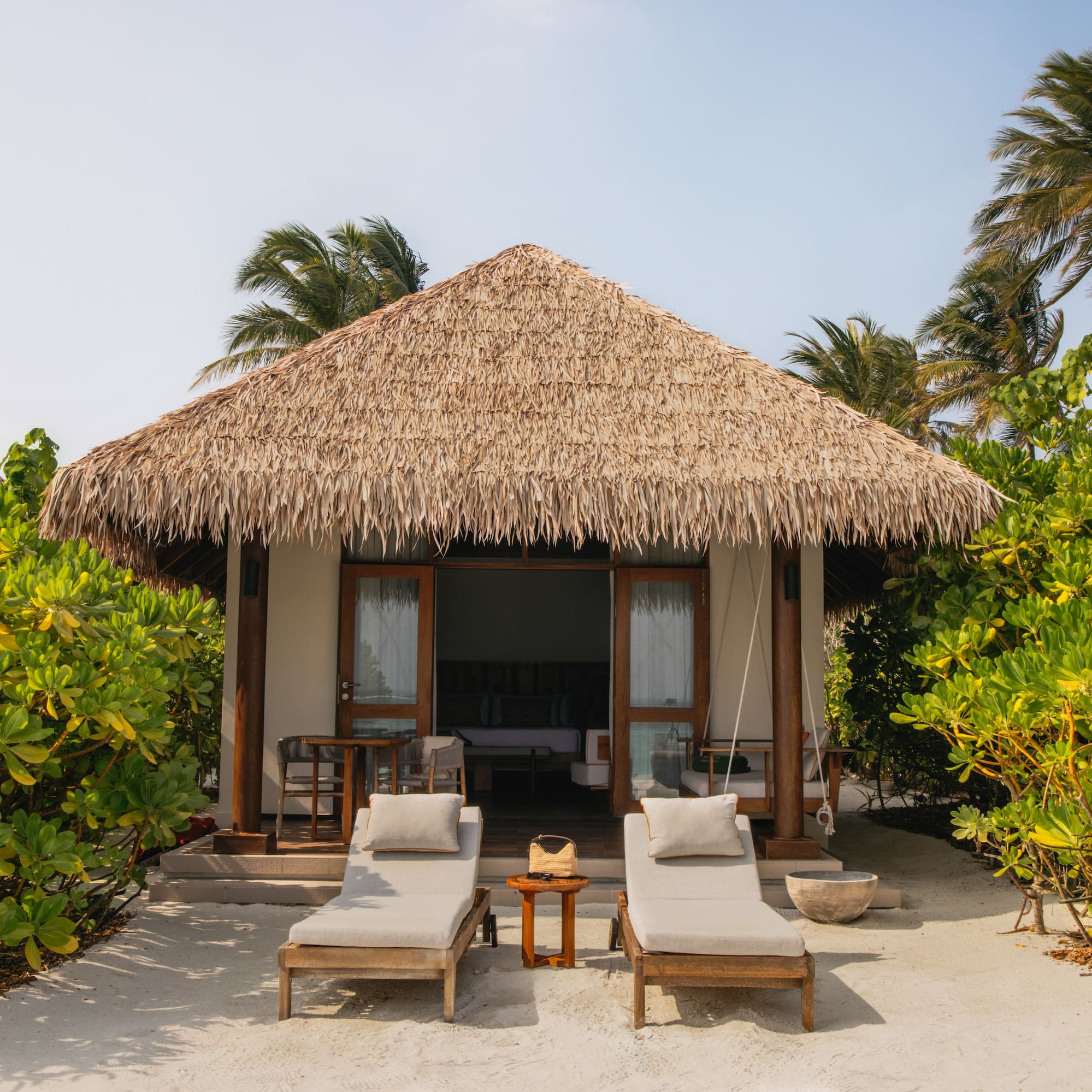 a small hut with lounge chairs and a thatched roof