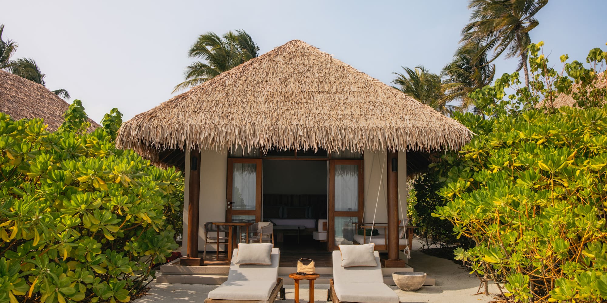 a small hut with lounge chairs and a thatched roof