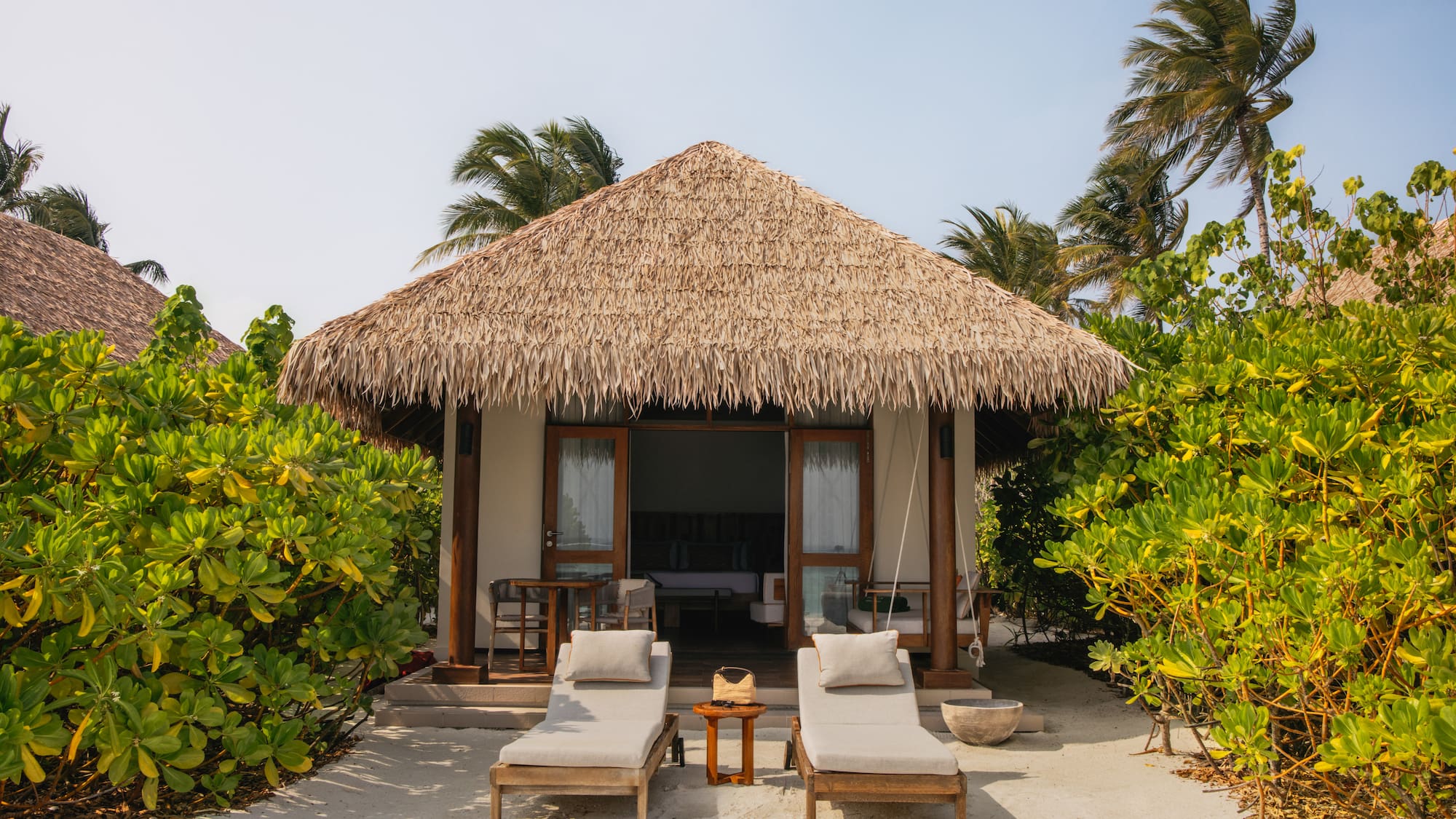 a small hut with lounge chairs and a thatched roof